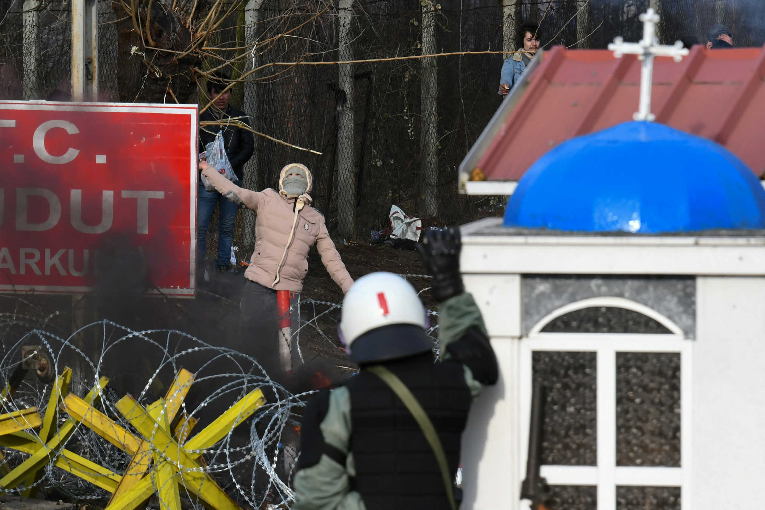 A hooded migrant who, along with other migrants wants to cross into Greece from Turkey's Pazarkule border crossing, prepares to throw a stone at a Greek riot police officer, in Kastanies, Greece, March 1, 2020. REUTERS