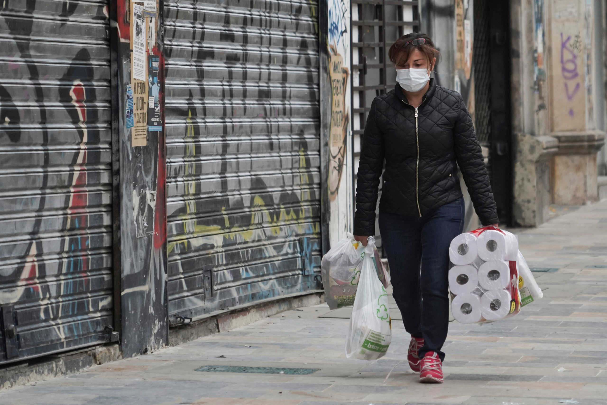A woman walks down a street carrying a toilet paper package during the four-day mandatory isolation decreed by the mayor of Bogota, as a preventive measure against the spread of the coronavirus disease (COVID-19), in Bogota, Colombia March 20, 2020. REUTERS