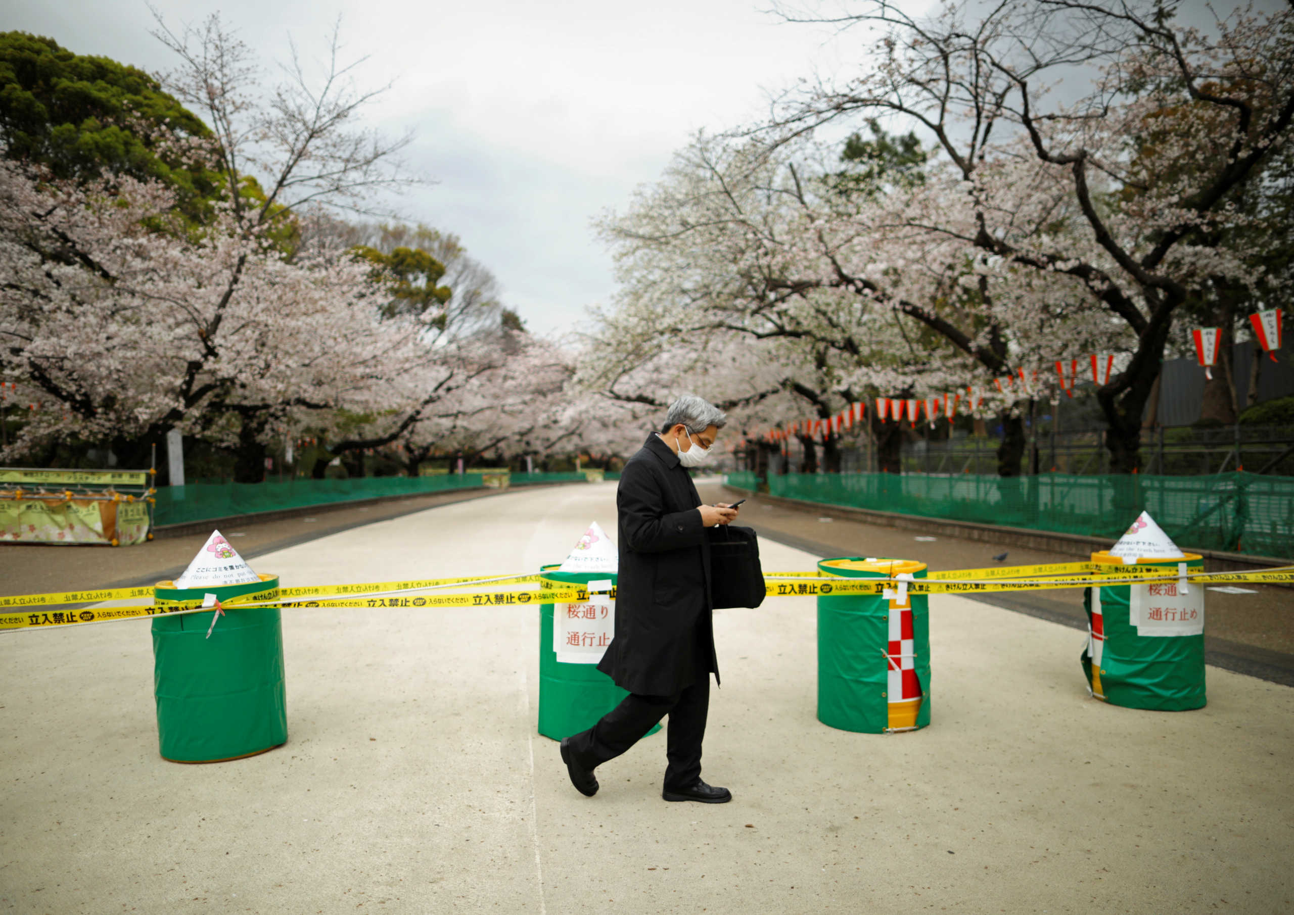 A man wearing a protective face mask, following an outbreak of the coronavirus disease (COVID-19), walks past a closed cherry blossom viewing spot during the first weekend after Tokyo Governor Yuriko Koike (not pictured) urged Tokyo residents to stay indoors in a bid to keep the coronavirus disease from spreading, at Ueno park in Tokyo, Japan March 28, 2020.    REUTERS