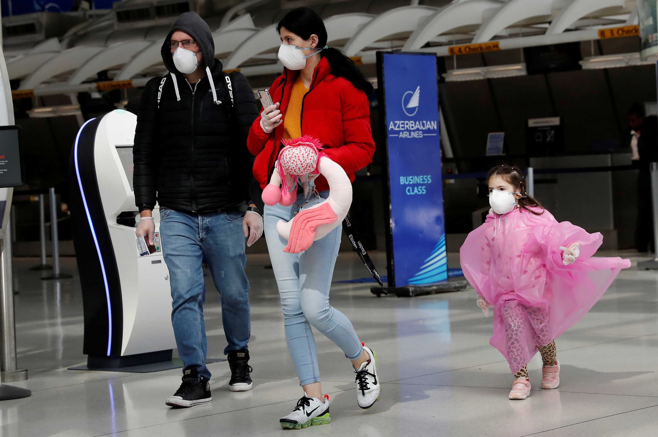 Air travelers walk with face maskst , after further cases of coronavirus were confirmed in New York, in Terminal 1 at JFK International Airport in New York, U.S., March 16, 2020. REUTERS