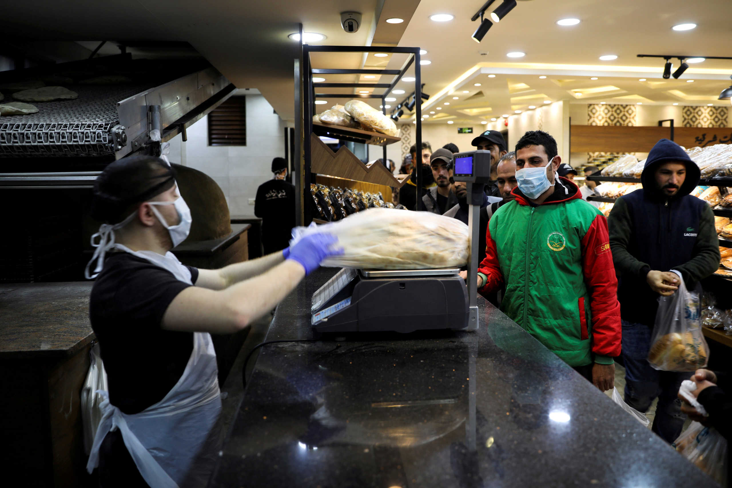 FILE PHOTO: People stand in line to buy bread at a bakery amid concerns over the coronavirus disease (COVID-19) in Amman, Jordan, March 17, 2020. REUTERS