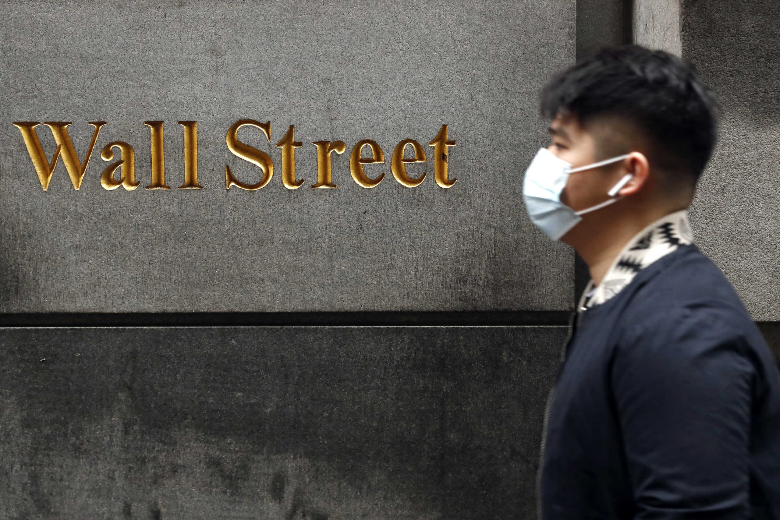 A man wears a protective mask as he walks on Wall Street during the coronavirus outbreak in New York City, New York, U.S., March 13, 2020. REUTERS