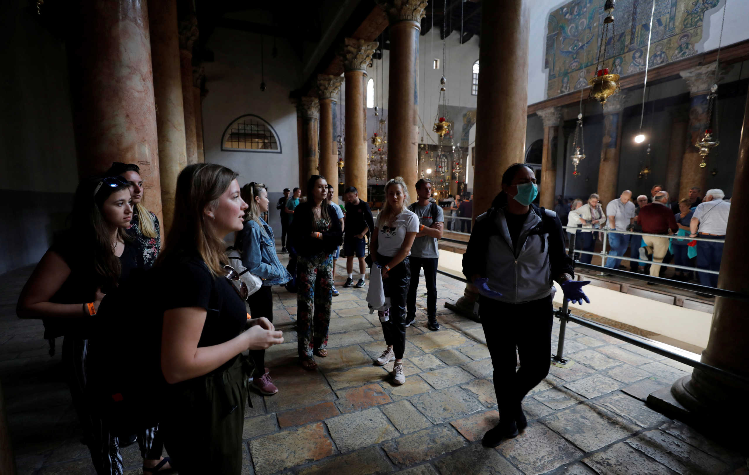 A tourist wearing a mask as a preventive measure against the coronavirus gestures as she visits the Church of the Nativity in Bethlehem in the Israeli-occupied West Bank March 5, 2020. REUTERS