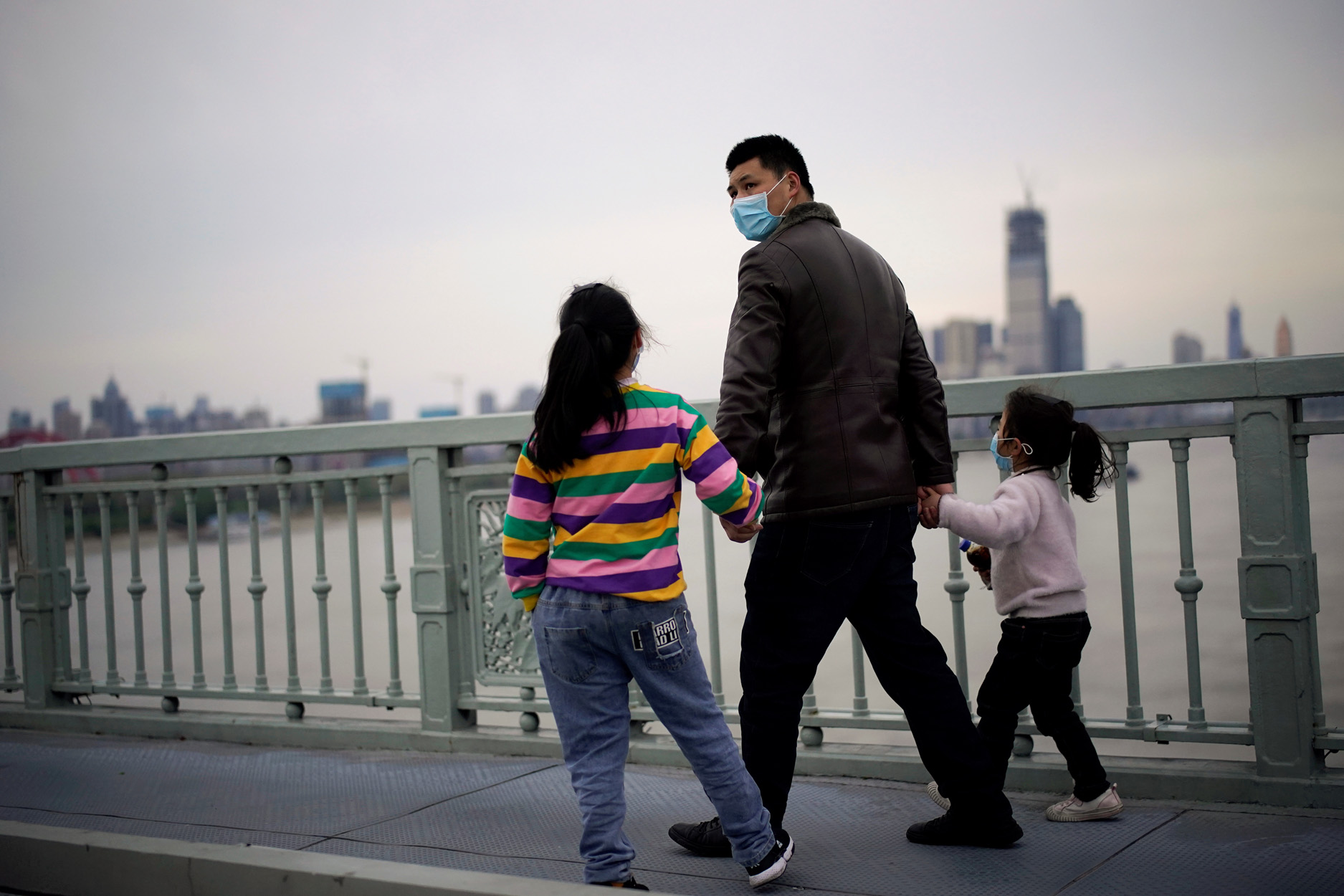 People wearing face masks walk on a bridge in Wuhan, Hubei province, the epicenter of China's coronavirus disease (COVID-19) outbreak, March 28, 2020. REUTERS
