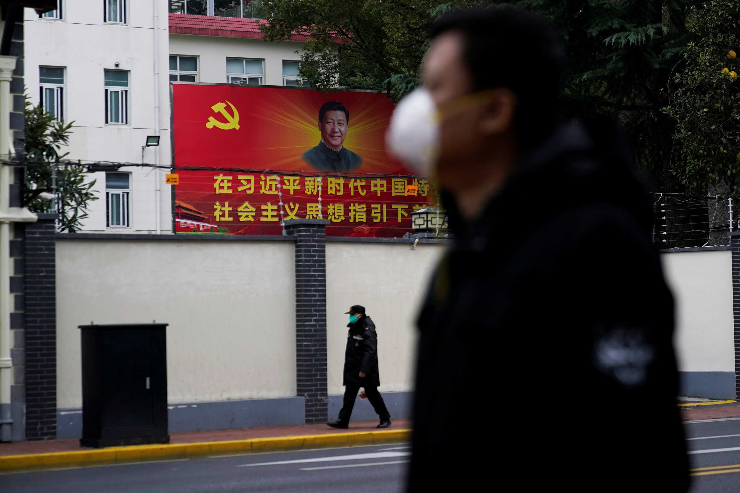 People wearing masks walk past a portrait of Chinese President Xi Jinping on a street as the country is hit by an outbreak of the novel coronavirus in Shanghai, China February 10, 2020. REUTERS