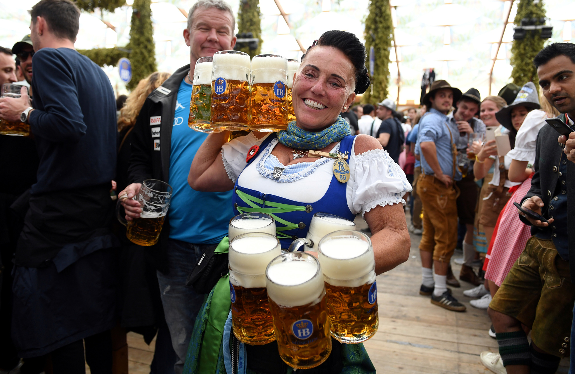 FILE PHOTO: A woman smiles as she carries the pints of beer at the opening day of the 186th Oktoberfest in Munich, Germany September 21, 2019. REUTERS