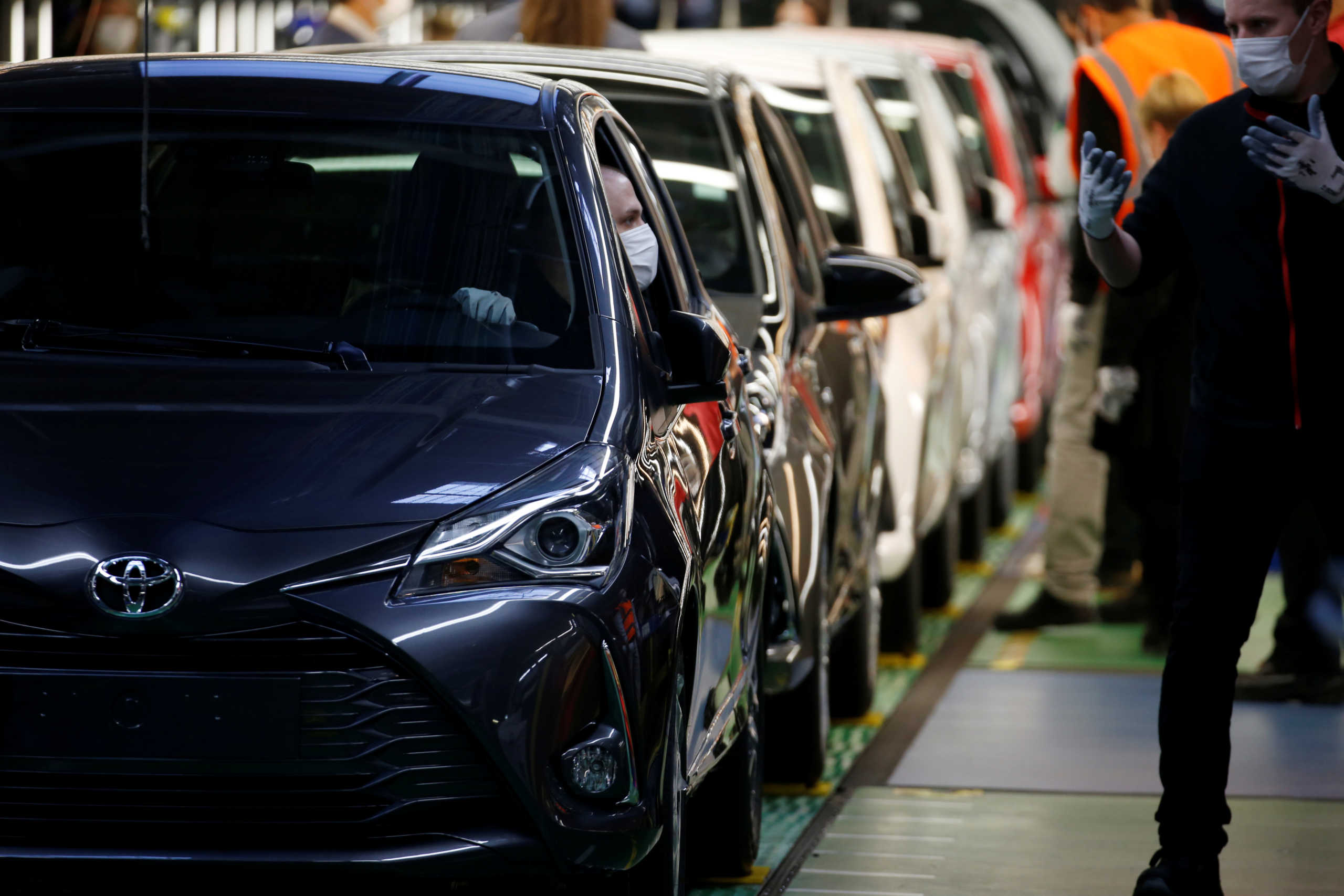 Employees wearing protective face masks are seen near the first Toyota Yaris cars leaving the automobile assembly line at the Toyota Motor Manufacturing France plant as it resumes its operations after five weeks of closure during a lockdown amid the coronavirus disease (COVID-19) outbreak, in Onnaing, France, April 23, 2020. REUTERS
