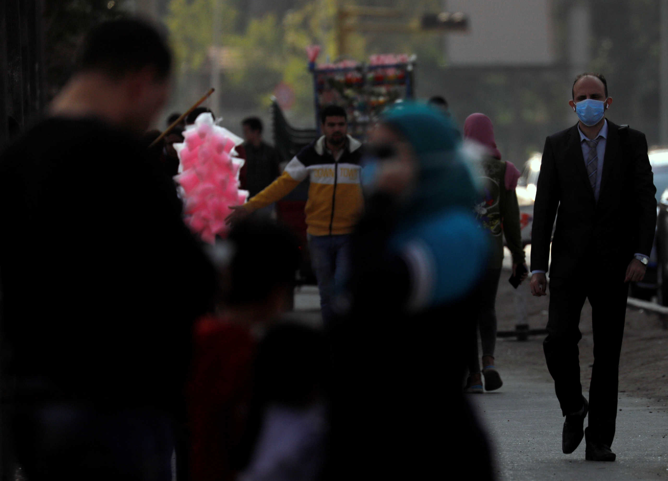 A man, wearing a protective mask due to the spread of coronavirus disease (COVID-19), looks to people celebrating a wedding party on a yacht along the bank of the Nile rive before the start of a night-time curfew in Cairo, Egypt, April 2, 2020. REUTERS
