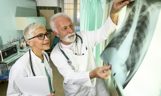 Two doctors, one male and one female, looking at a COVID-19 infected-patient's lungs x-ray image.