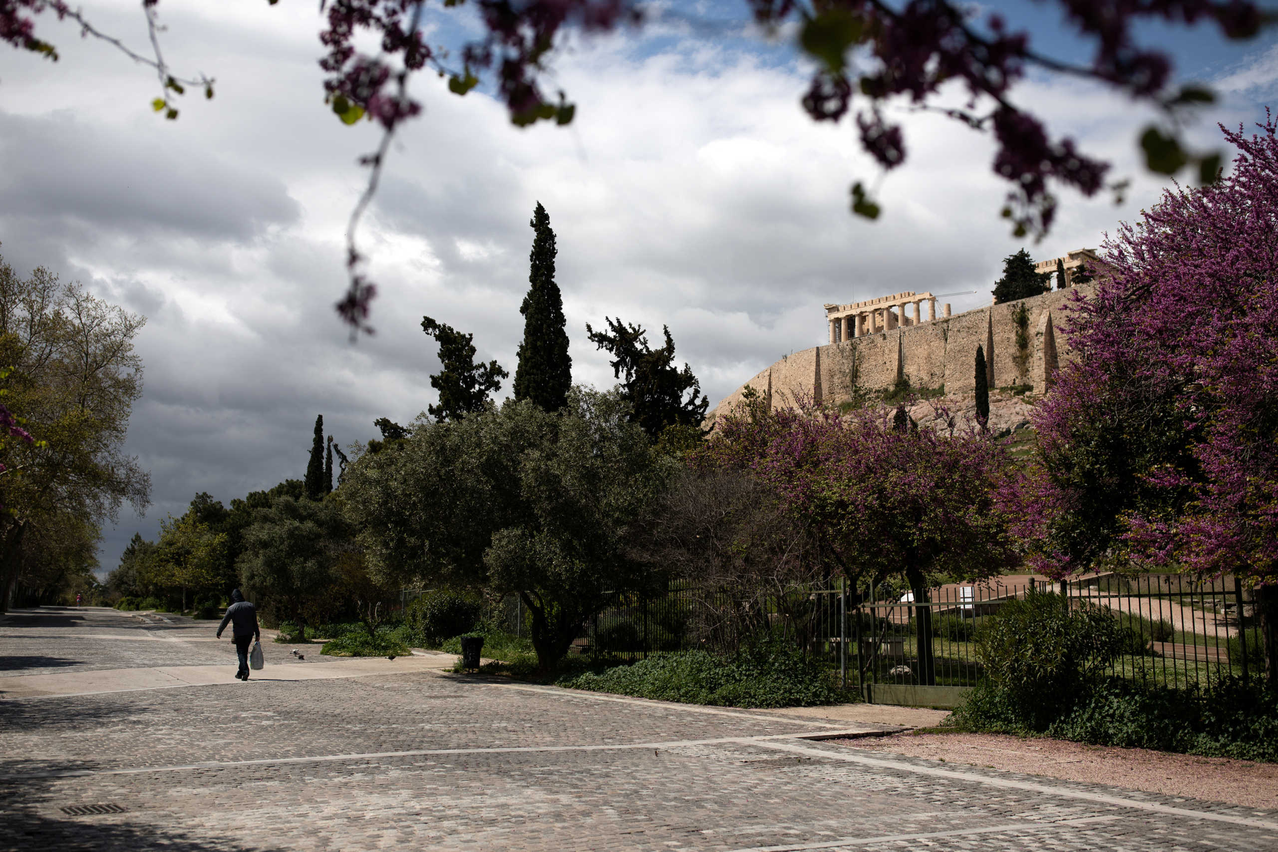 A man carrying a bag of goods walks on an empty pedestrian street under the Acropolis hill, during the coronavirus disease (COVID-19) outbreak, in Athens, Greece, April 7, 2020. REUTERS