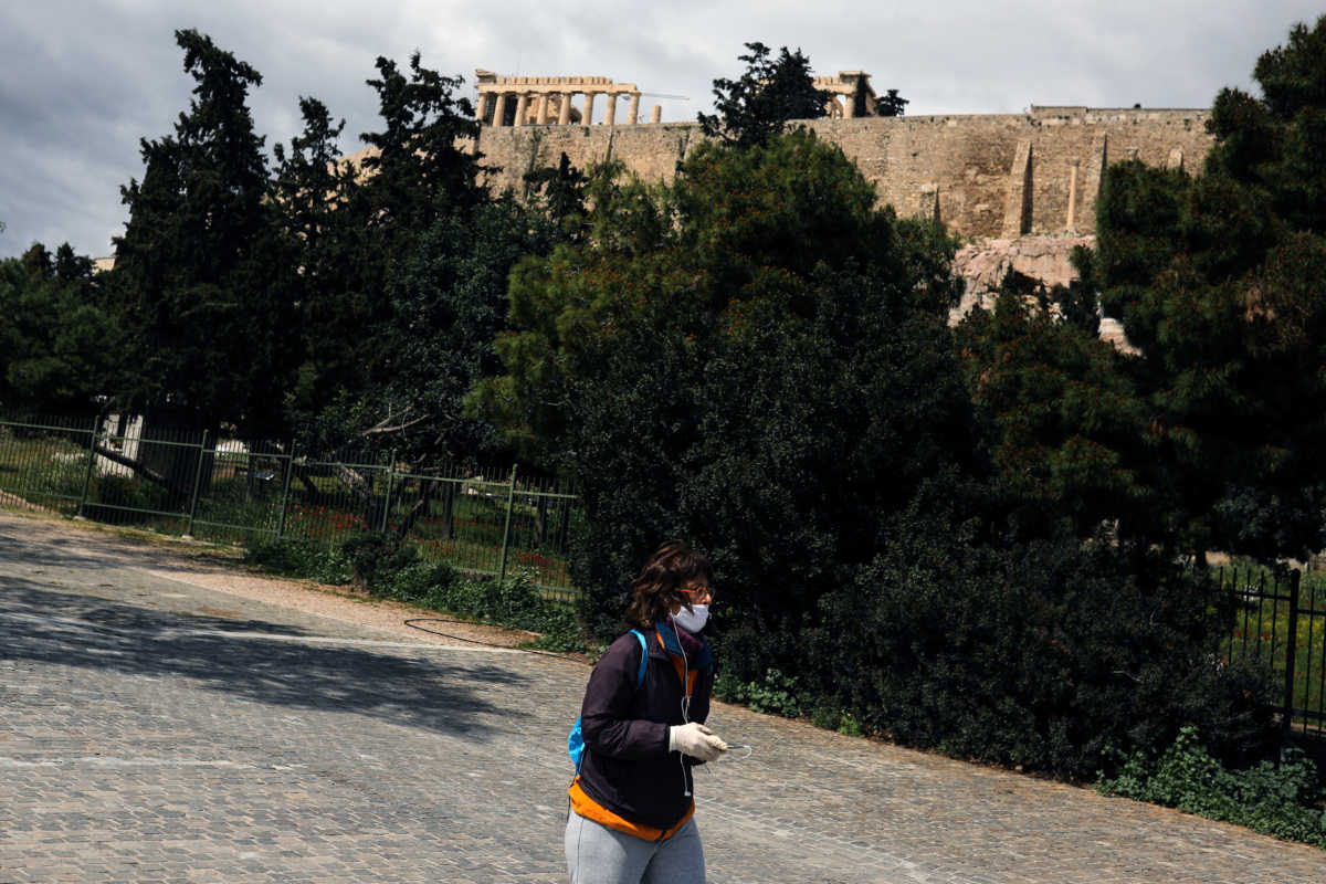 A woman wearing a protective face mask walks on a pedestrian street under the Acropolis hill, during the coronavirus disease (COVID-19) outbreak, in Athens, Greece, April 7, 2020. REUTERS