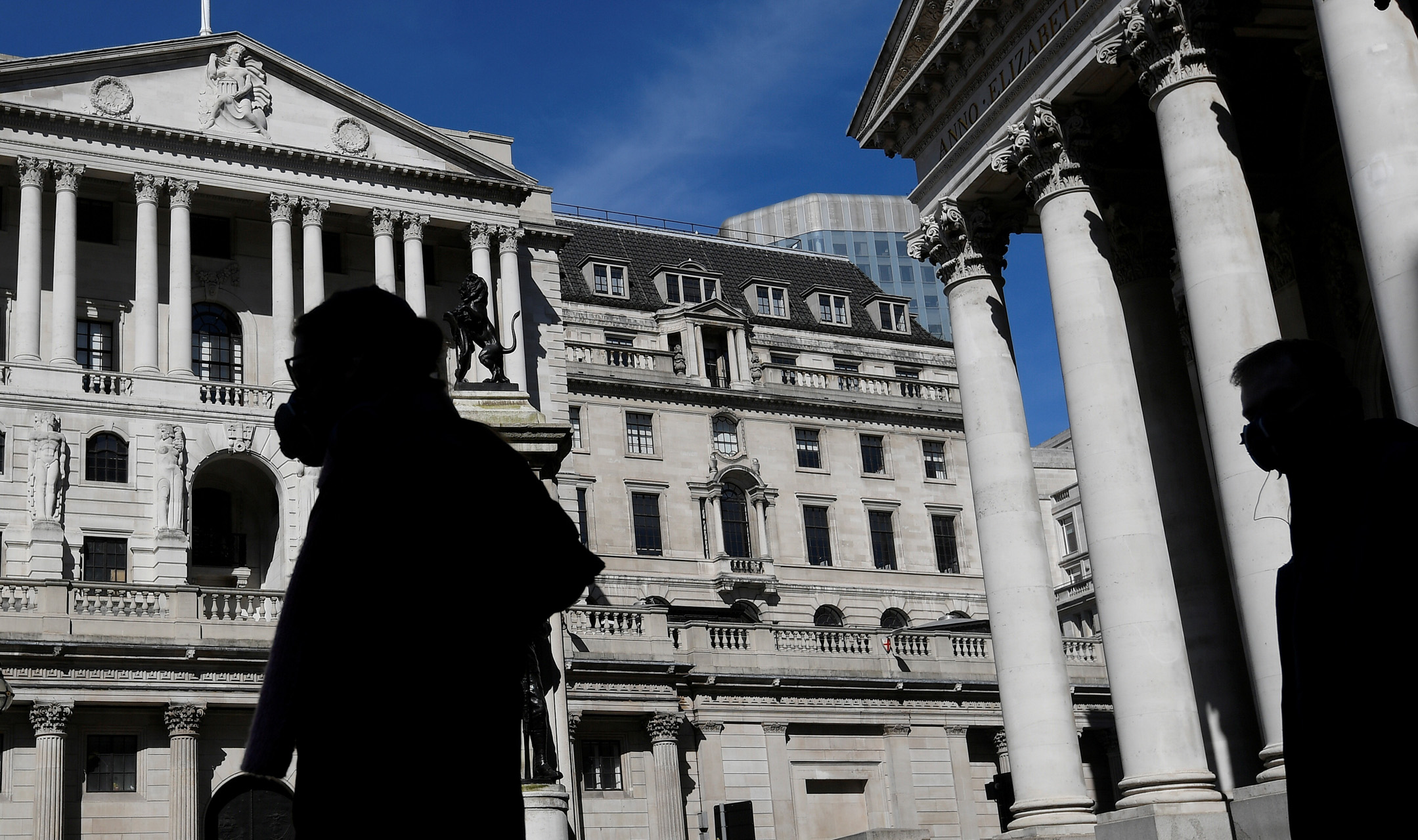 FILE PHOTO: People wearing masks walk past the Bank of England, as the spread of the coronavirus disease (COVID-19) continues, in London, Britain, March 23, 2020. REUTERS