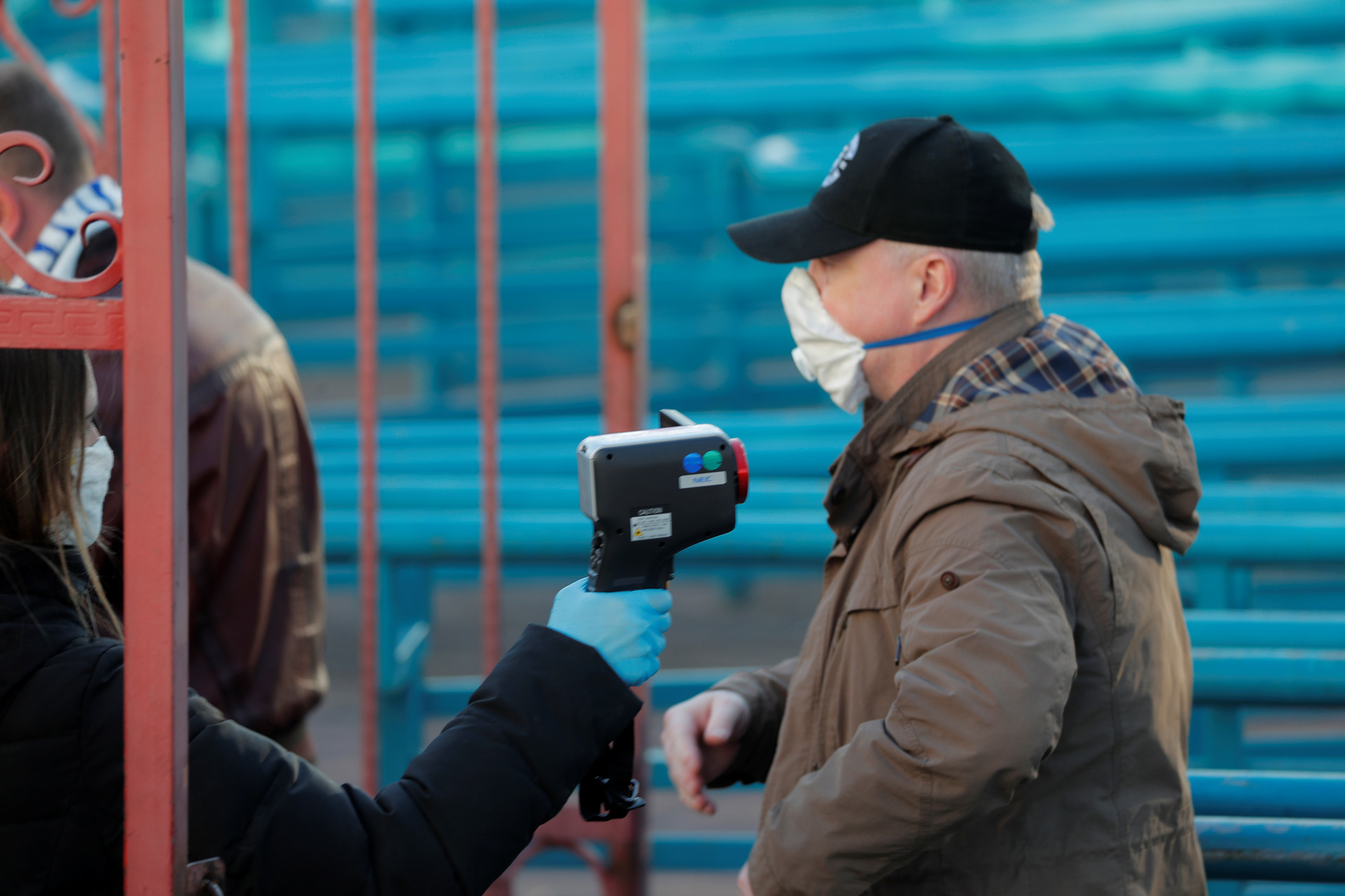 Soccer Football - Vysheyshaya Liga - Dynamo Brest v Isloch Minsk - OSK Brestsky Stadium, Brest, Belarus, April 12, 2020   Staff takes a fan's temperature wearing a protective face mask despite most sport being cancelled around the world as the spread of coronavirus disease (COVID19) continues   REUTERS