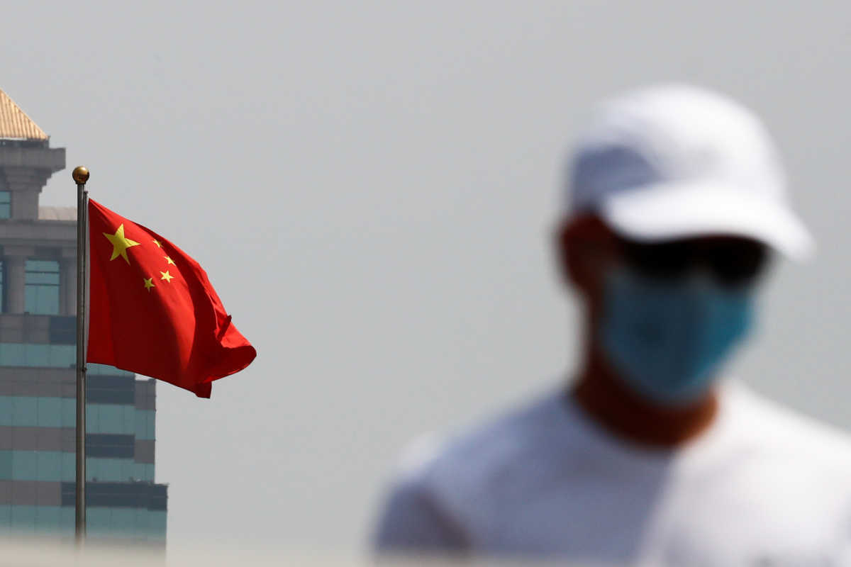 A man walks near the Chinese national flag in Beijing, China April 29, 2020. REUTERS