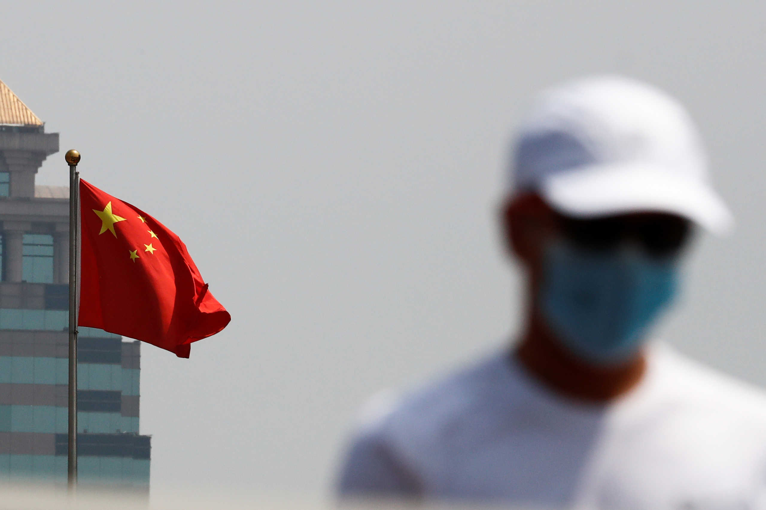 A man walks near the Chinese national flag in Beijing, China April 29, 2020. REUTERS