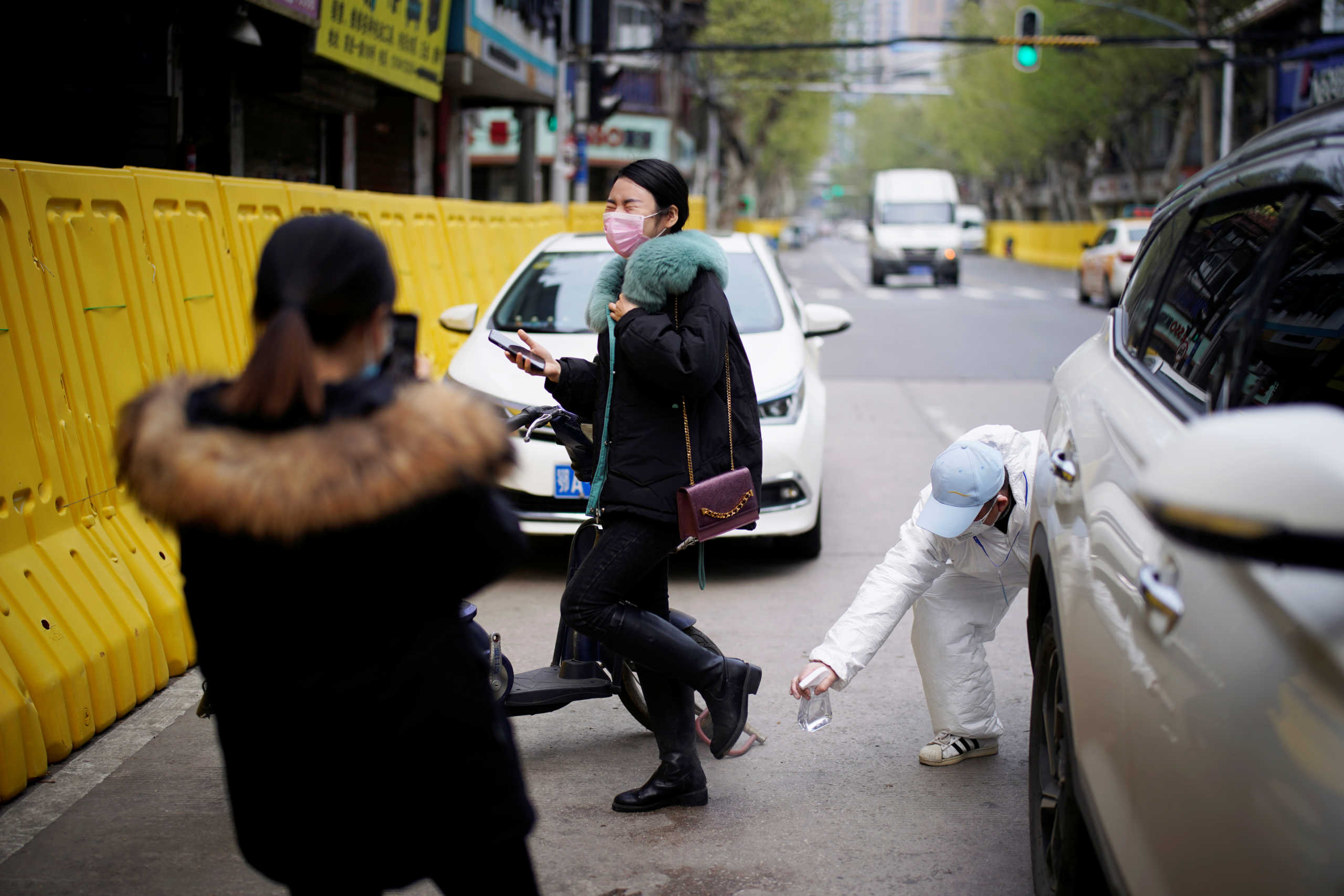 A driver wearing a protective suit disinfects a woman on a street in Wuhan, Hubei province, the epicentre of China's coronavirus disease (COVID-19) outbreak, April 3, 2020. REUTERS