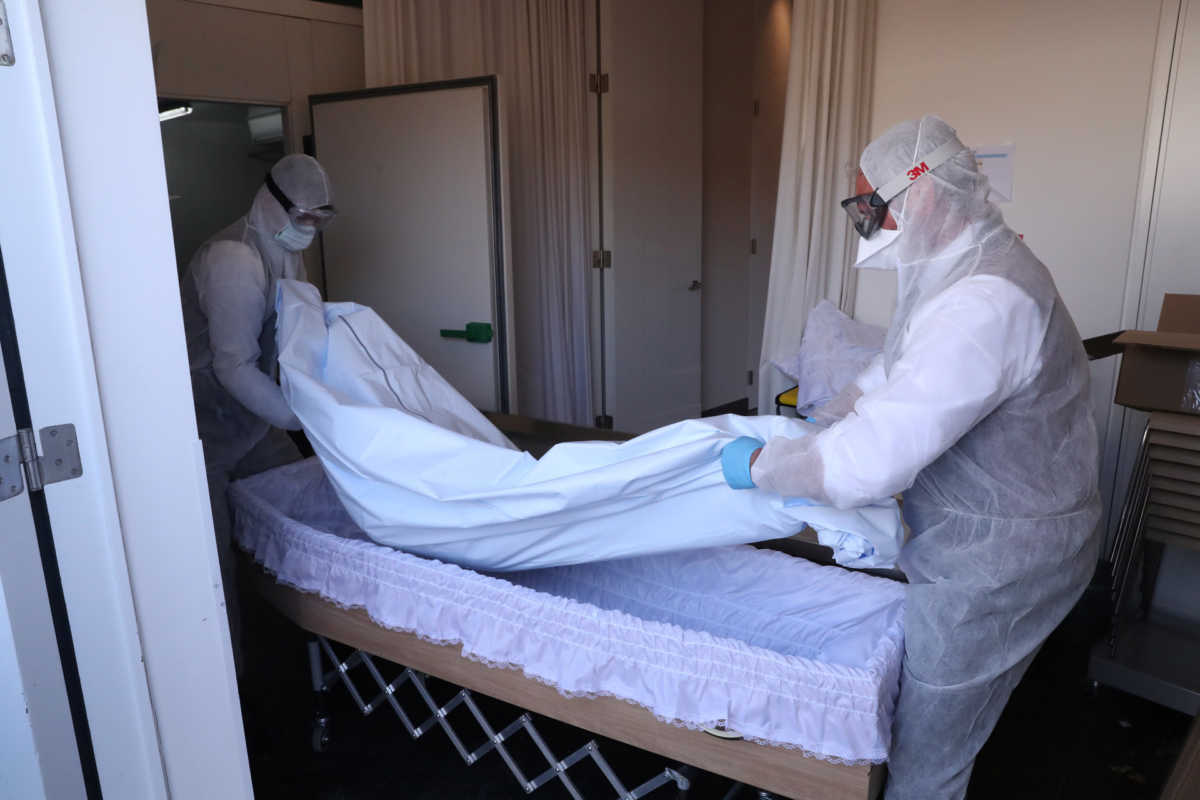 Mortuary workers put the body of a victim of the coronavirus disease (COVID-19) inside a coffin, in Brussels, Belgium April 10, 2020. REUTERS