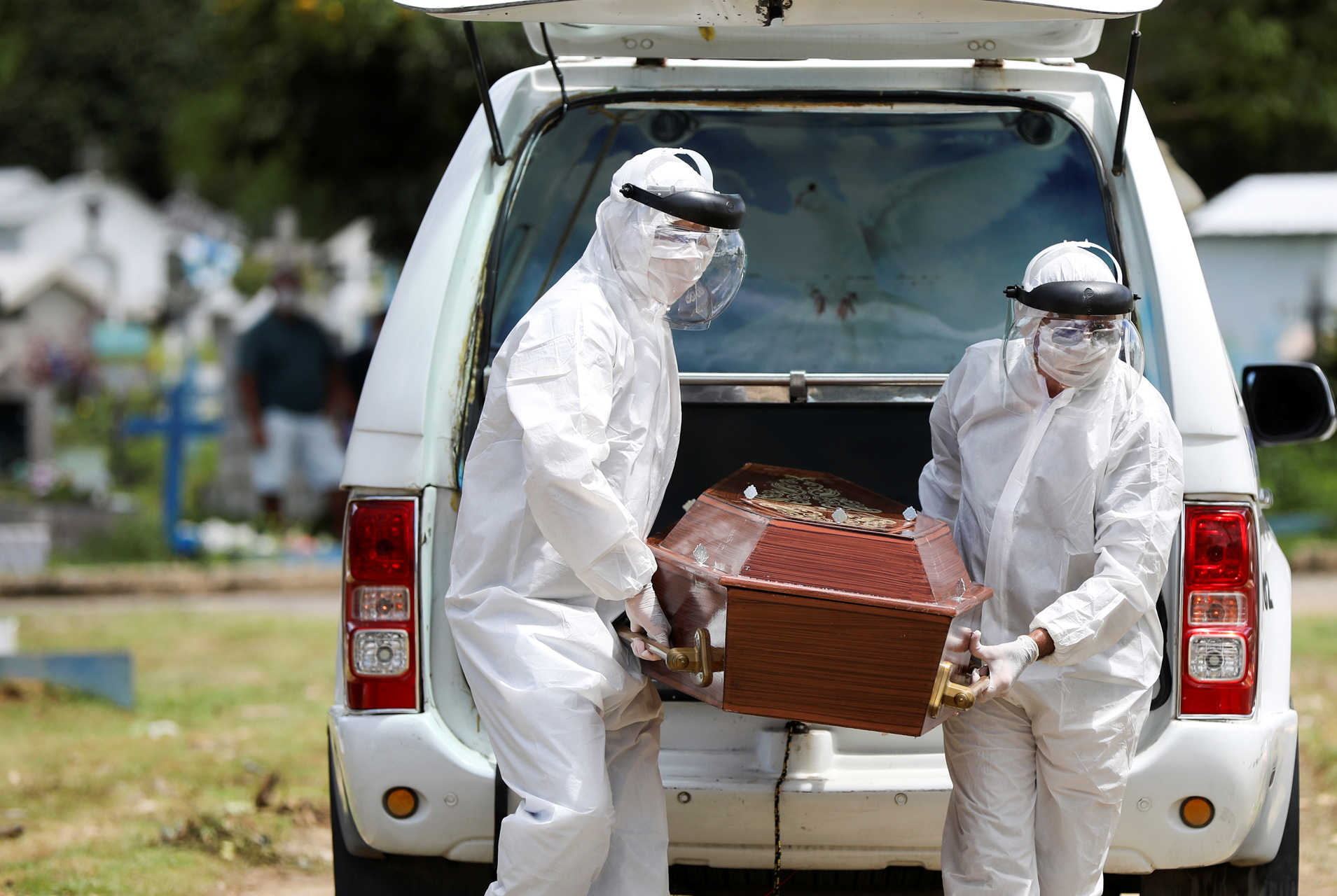Workers of a funeral parlor wearing protective suits carry the coffin of 68-years-old Natalina Cardoso Bandeira, who passed away due to coronavirus disease (COVID-19), at the Parque Taruma cemetery in Manaus, Brazil, April 10, 2020. REUTERS