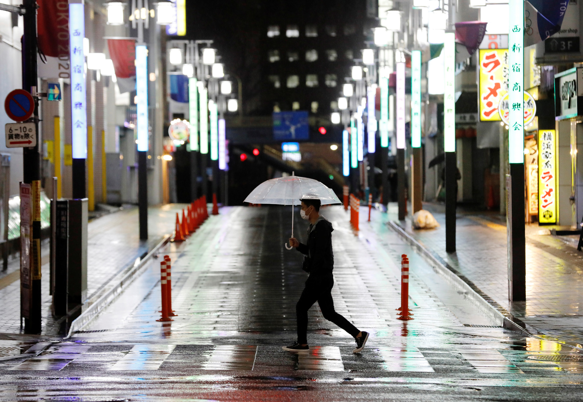 A man wearing a face mask makes his way in the rain on a nearly empty street after the government announced a state of emergency for the capital and some prefectures following the coronavirus disease (COVID-19) outbreak, in Tokyo, Japan April 16, 2020. REUTERS