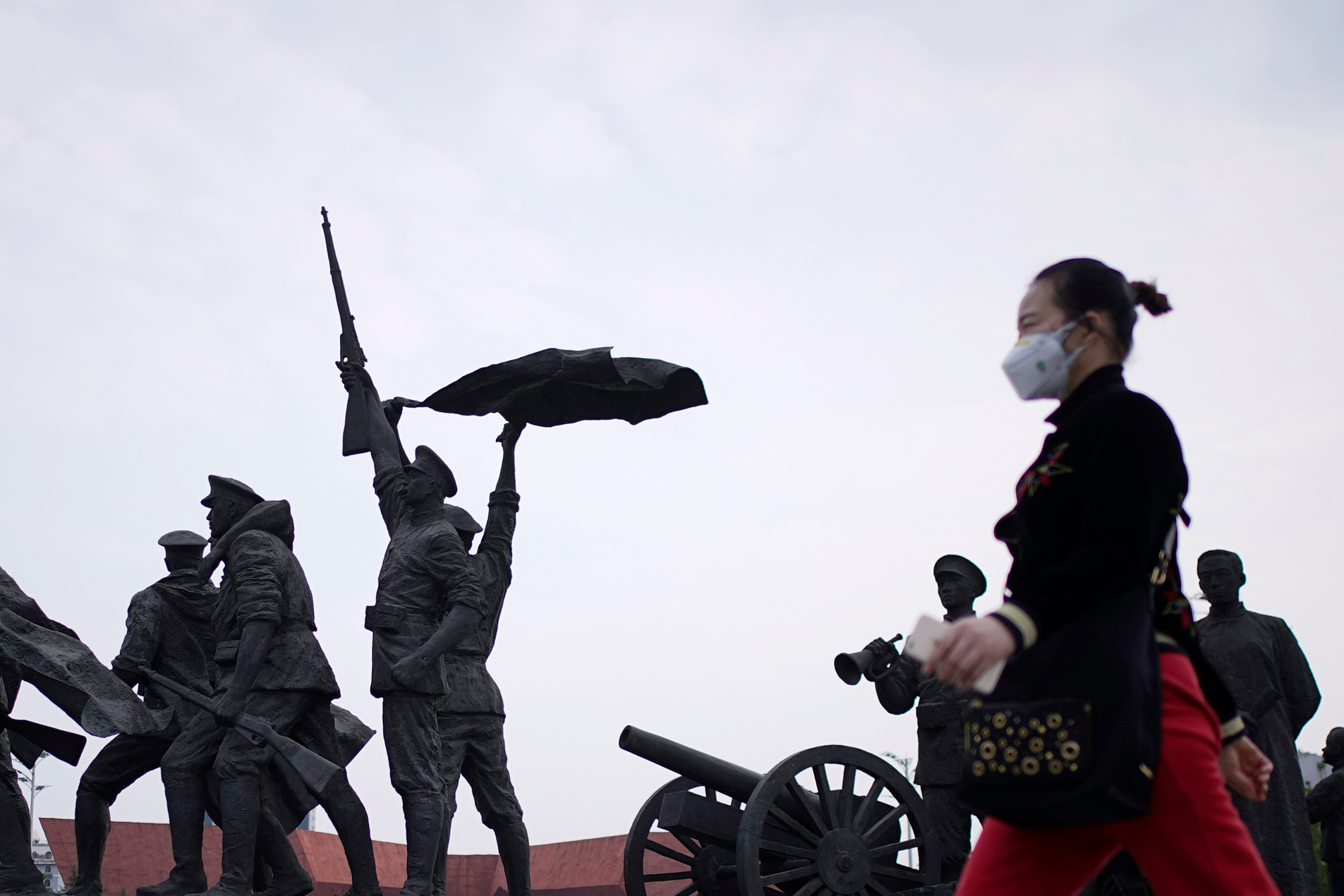 A resident wearing a face mask walks past statue symbolising Xinhai Revolution, a revolution that toppled China's last emperor in 1911, in Wuhan, Hubei province, the epicentre of China's coronavirus disease (COVID-19) outbreak, April 6, 2020. REUTERS
