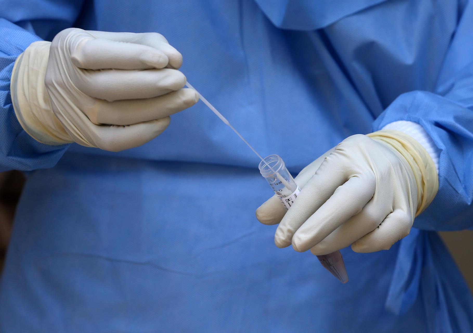 A doctor wearing a protective suit stores a swab in a test tube after taking it from a man to test for coronavirus disease (COVID-19), at a residential area in Mumbai, India, April 8, 2020. REUTERS