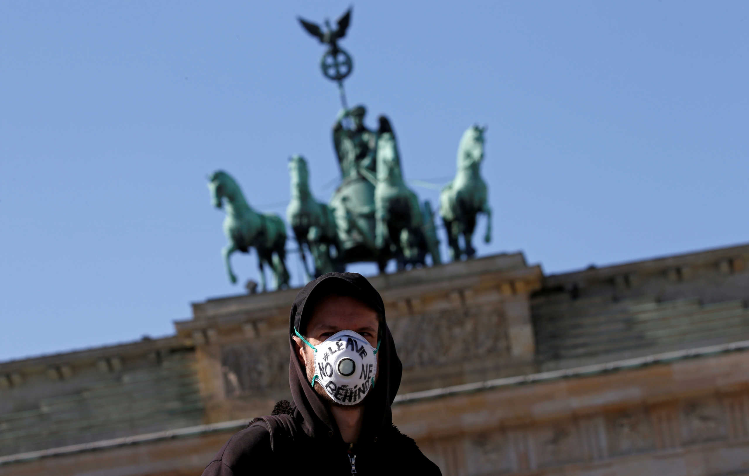 FILE PHOTO: A man wears a face mask during a protest demanding to take refugees from camps affected by the coronavirus disease (COVID-19) outbreak, in front of Brandenburg Gate in Berlin, Germany April 5, 2020. REUTERS