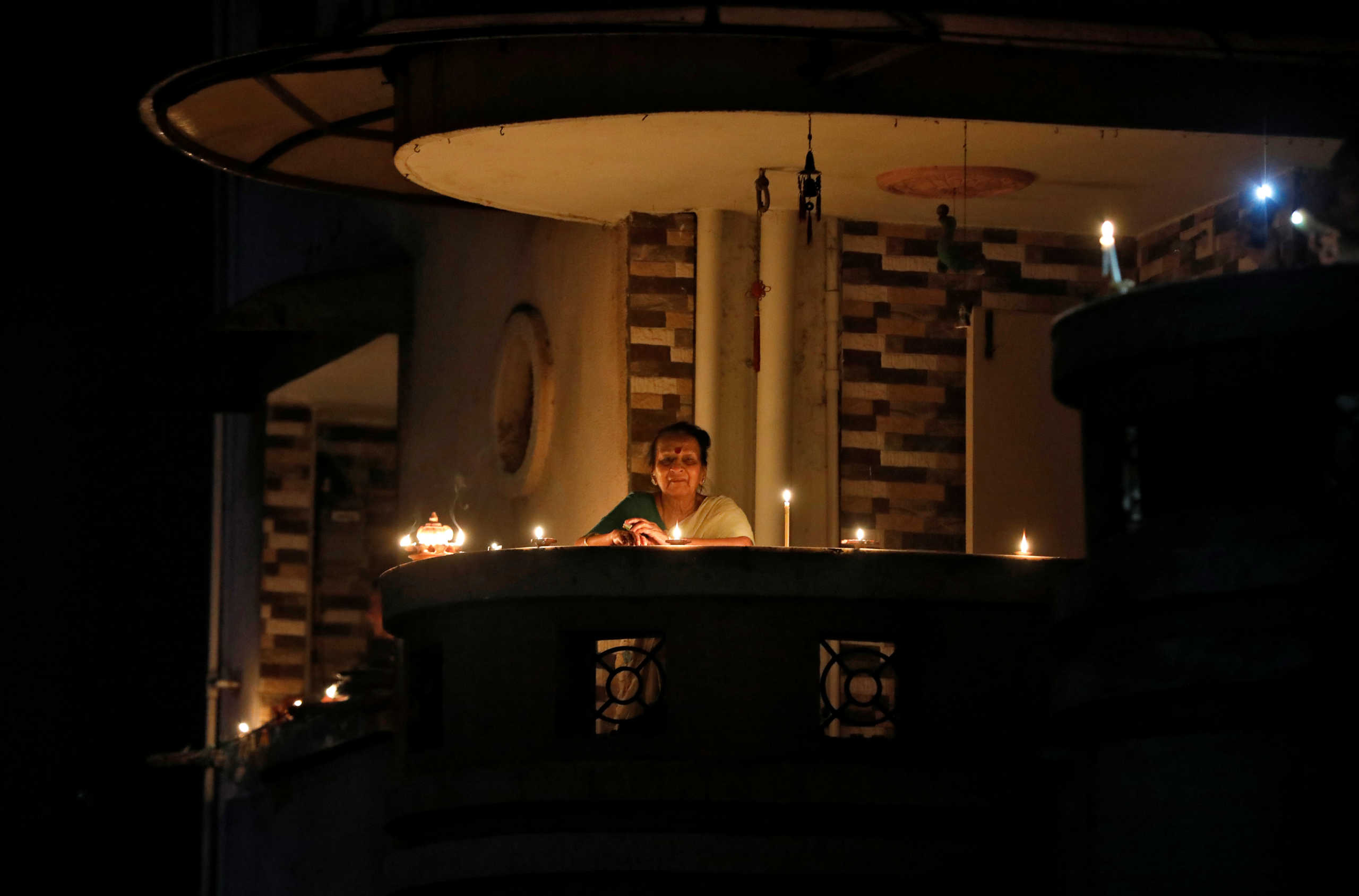 A woman stands on a balcony after lighting an oil lamps after Indian Prime Minister Narendra Modi appealed to Indians to turn out their lights for nine minutes at 9 p.m. to mark the coronavirus fight, during a lockdown to slow the spreading of coronavirus disease (COVID-19), in Ahmedabad, India, April 5, 2020. REUTERS