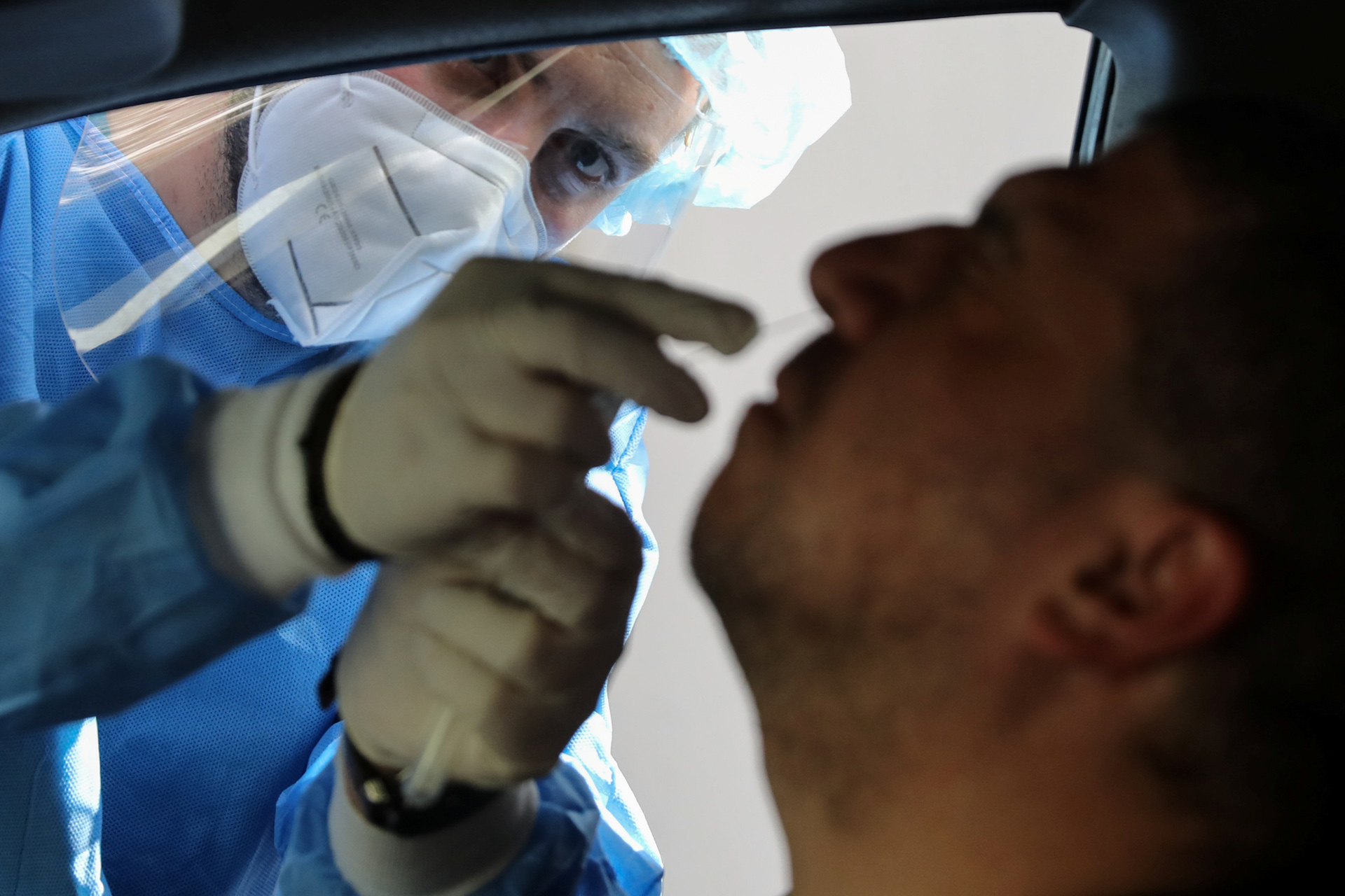 A health worker takes a nasal swab from a driver at a coronavirus drive-through testing station, during the coronavirus disease (COVID-19) outbreak, in Nicosia, Cyprus April 17, 2020. REUTERS