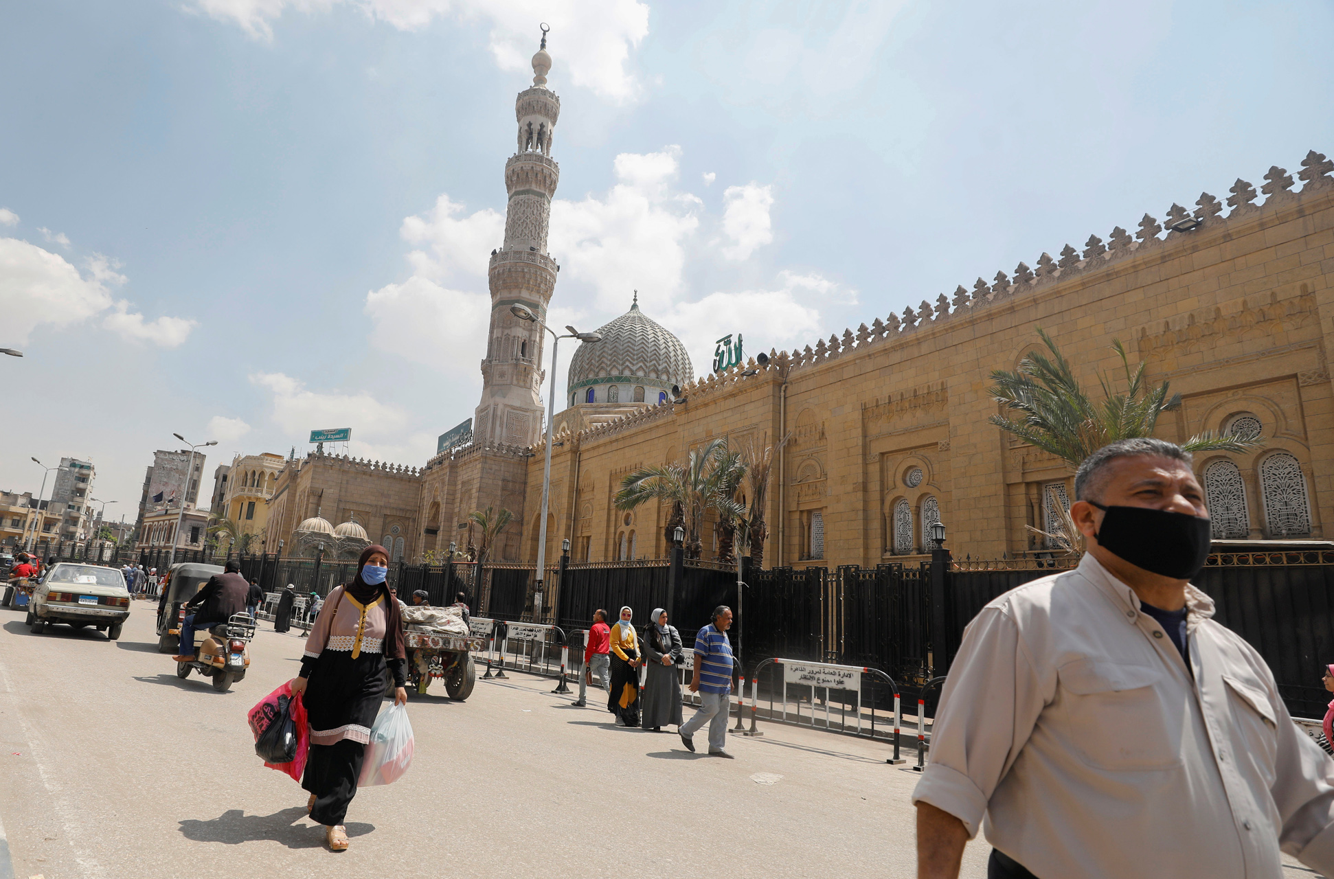 People wear protective face masks amid concerns over the coronavirus disease (COVID-19) walk in front of the closed El Sayeda Zainab Mosque near markets that sell traditional Ramadan lanterns, in Cairo, Egypt, April 12, 2020. REUTERS