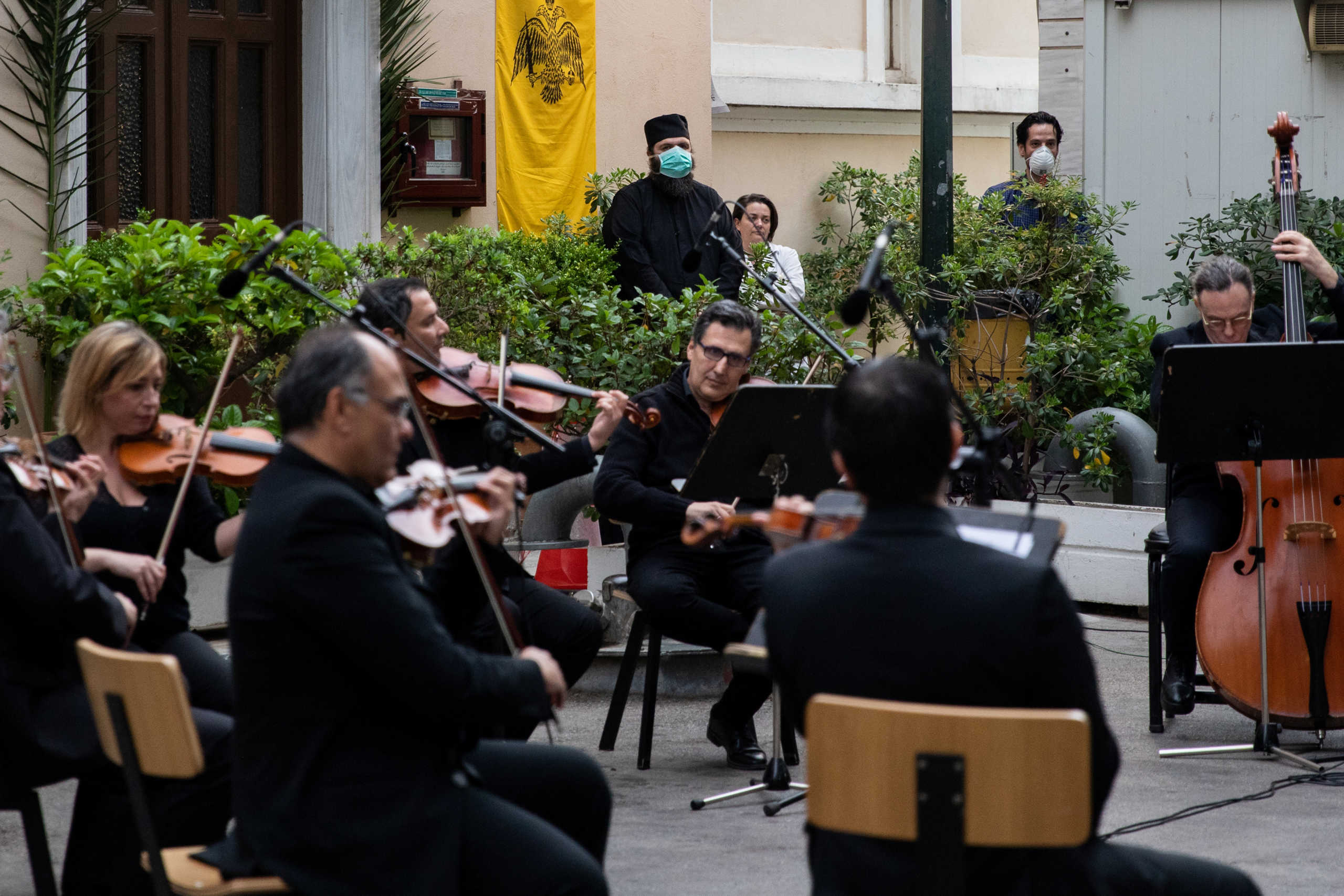 A Greek Orthodox priest wearing a face mask watches a concert of the Hellenic Broadcasting Corporation (ERT) orchestra at the premises of Evangelismos hospital, following the coronavirus disease (COVID-19) outbreak in Athens, Greece, April 20, 2020. REUTERS