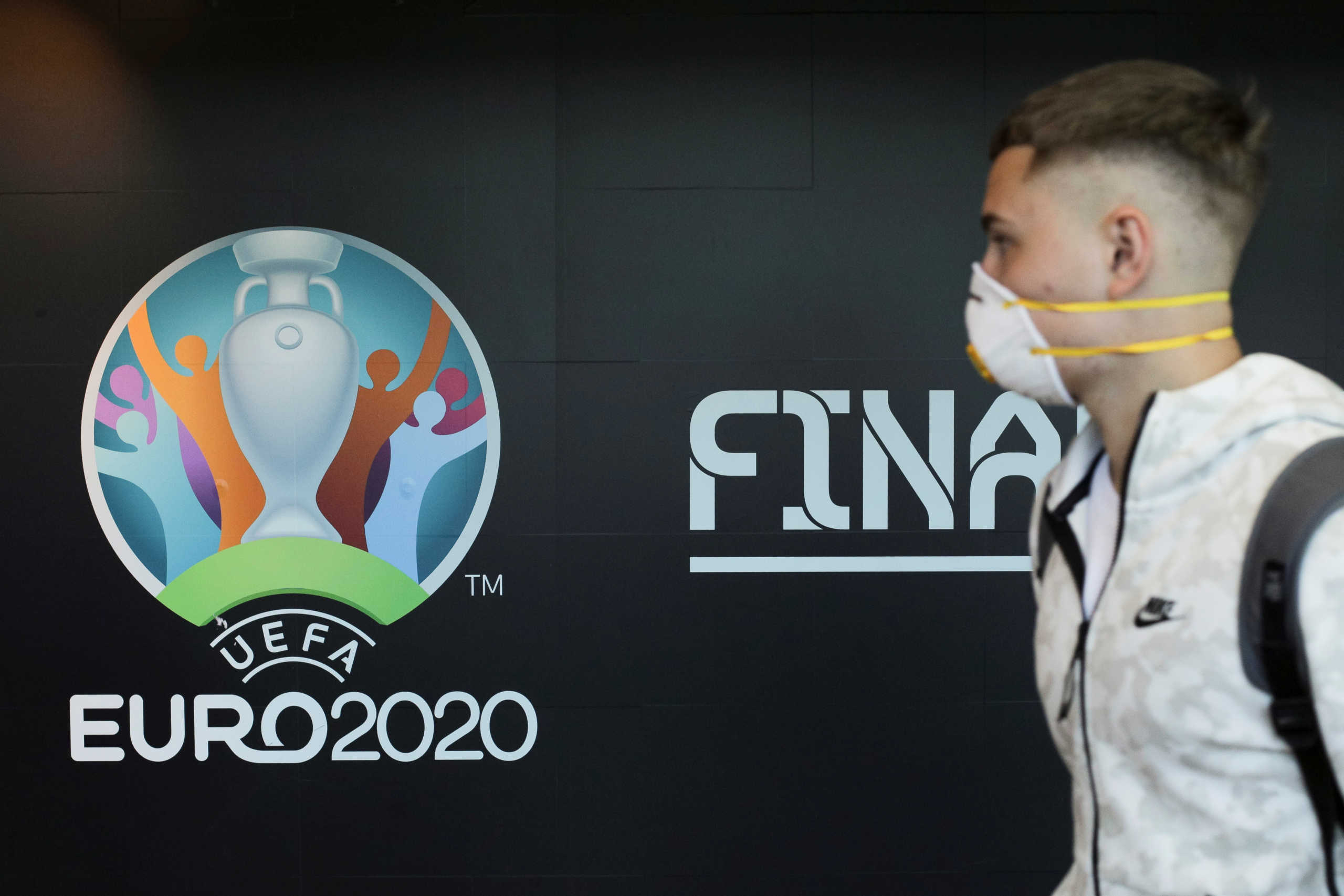 Travellers pass by a logo of the 2020 UEFA European Football Championship displayed on a wall inside Bucharest Henri Coanda International Airport, in Otopeni, Romania, March 16, 2020. Inquam Photos