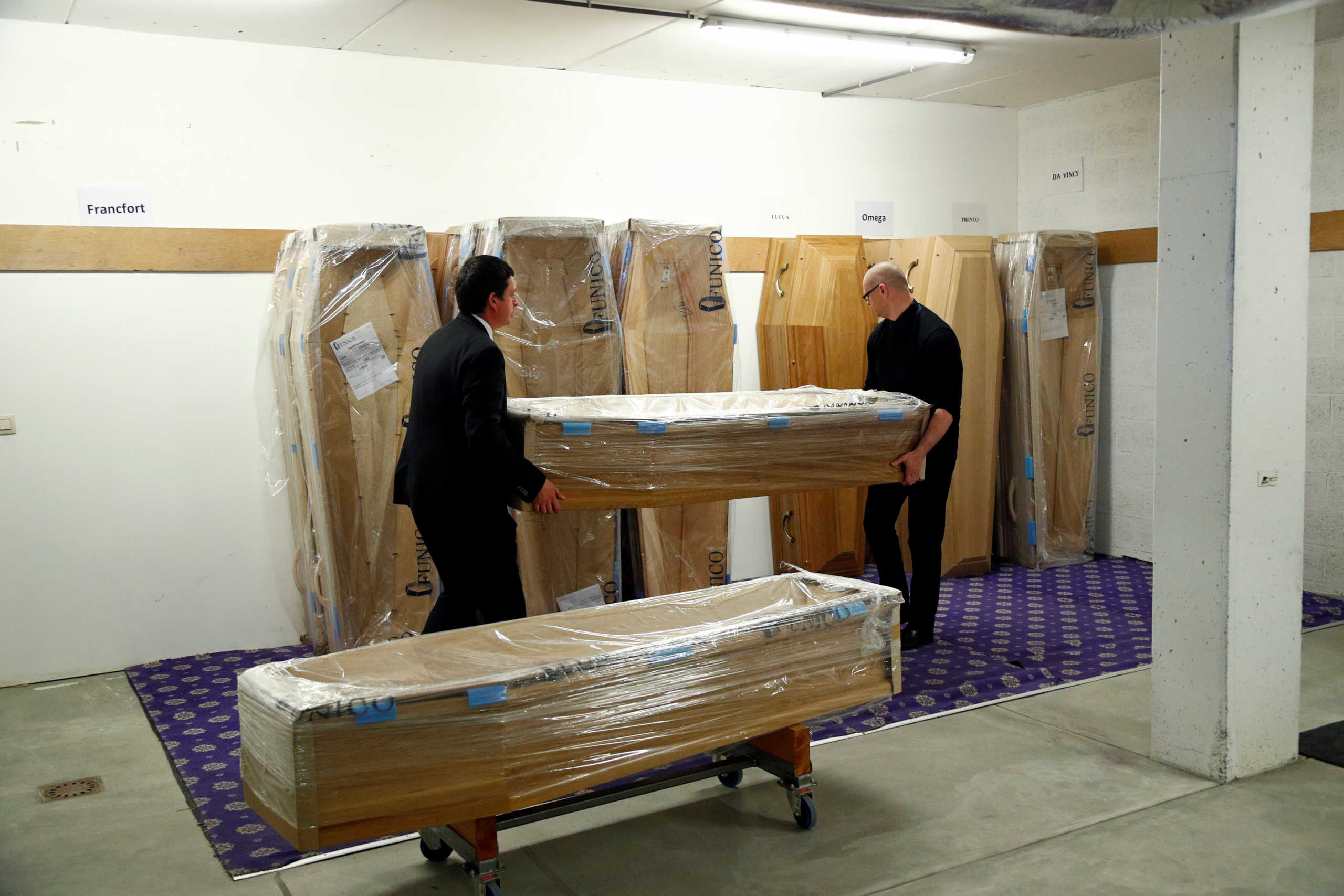 Mortuary workers transport the coffins as the spread of the coronavirus disease (COVID-19) continues, at a funeral service company in Arlon, Belgium April 7, 2020. REUTERS