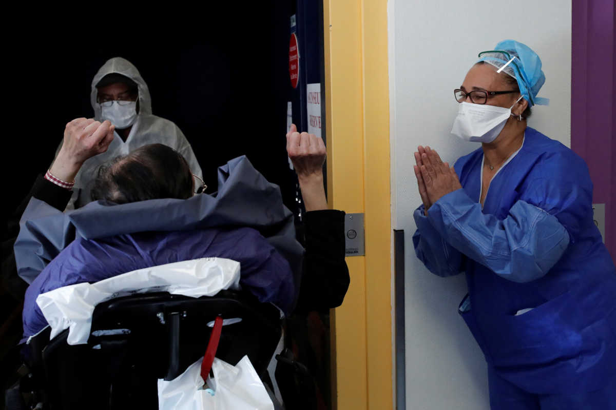 Medical staff member applauds patient Mang Phother, 61, who spent 16 days in the Intensive Care Unit (ICU) for the coronavirus disease (COVID-19), as he leaves the Clinique de l'Estree private hospital in Stains near Paris as the spread of the coronavirus disease continues in France, April 23, 2020.   REUTERS