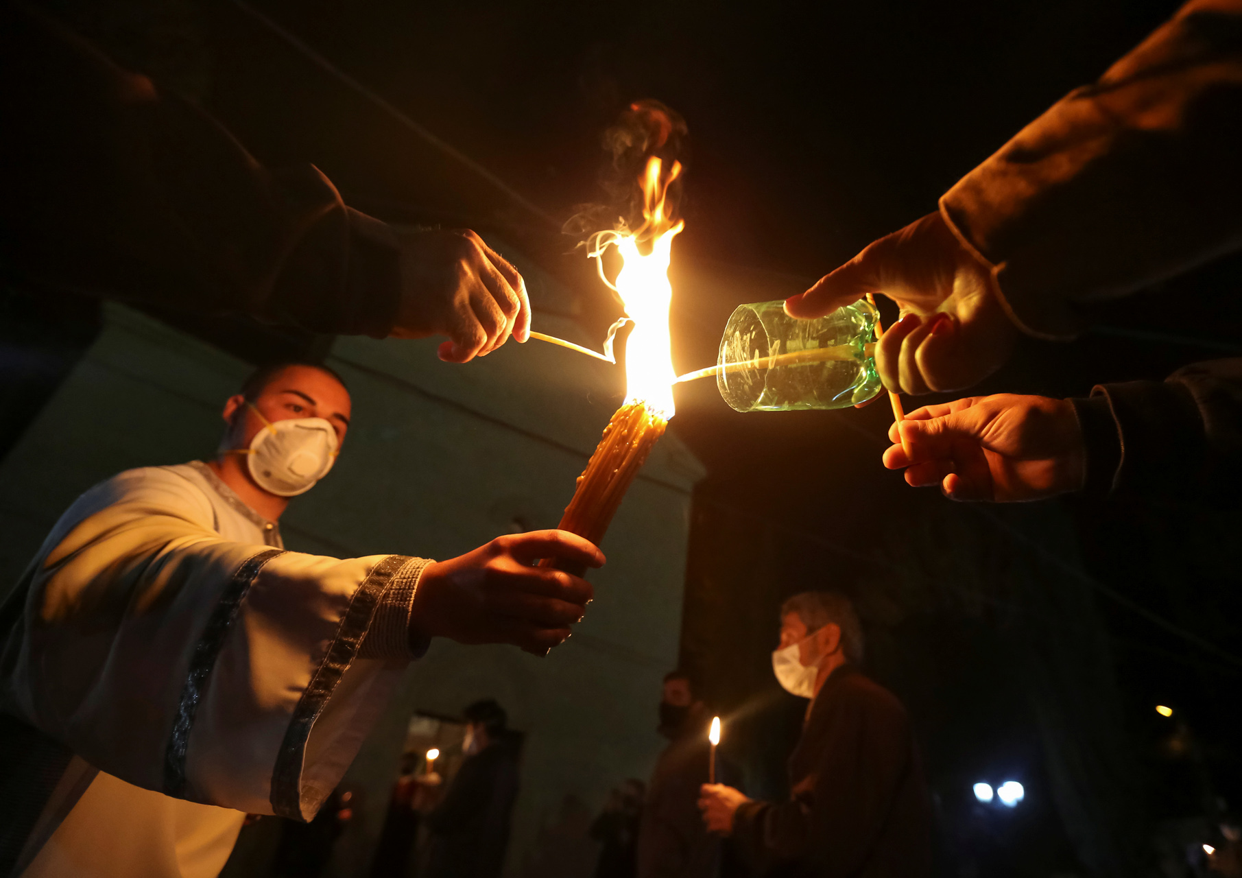 A clergyman and believers wearing protective masks hold candles outside a church during an Orthodox Easter service, amid the coronavirus disease (COVID-19) outbreak in Marneuli, Georgia April 19, 2020. REUTERS