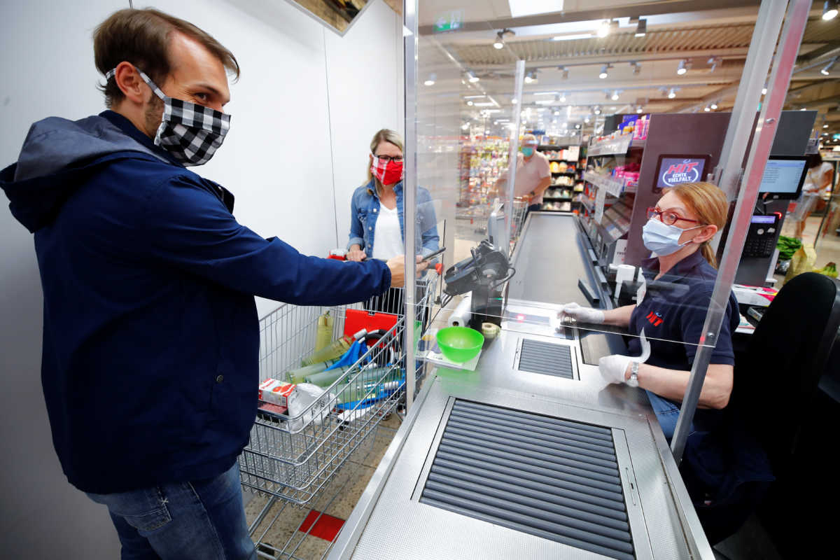 A man pays with his mobile phone at the checkout in a supermarket, after the federal state of North Rhine-Westphalia decided to make wearing protective masks obligatory in shops and public transportation to fight the spread of the coronavirus disease (COVID-19), in Bad Honnef near Bonn, Germany, April 27, 2020. REUTERS