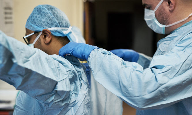 Shot of two surgeons helping each other get dressed in preparation for a surgery