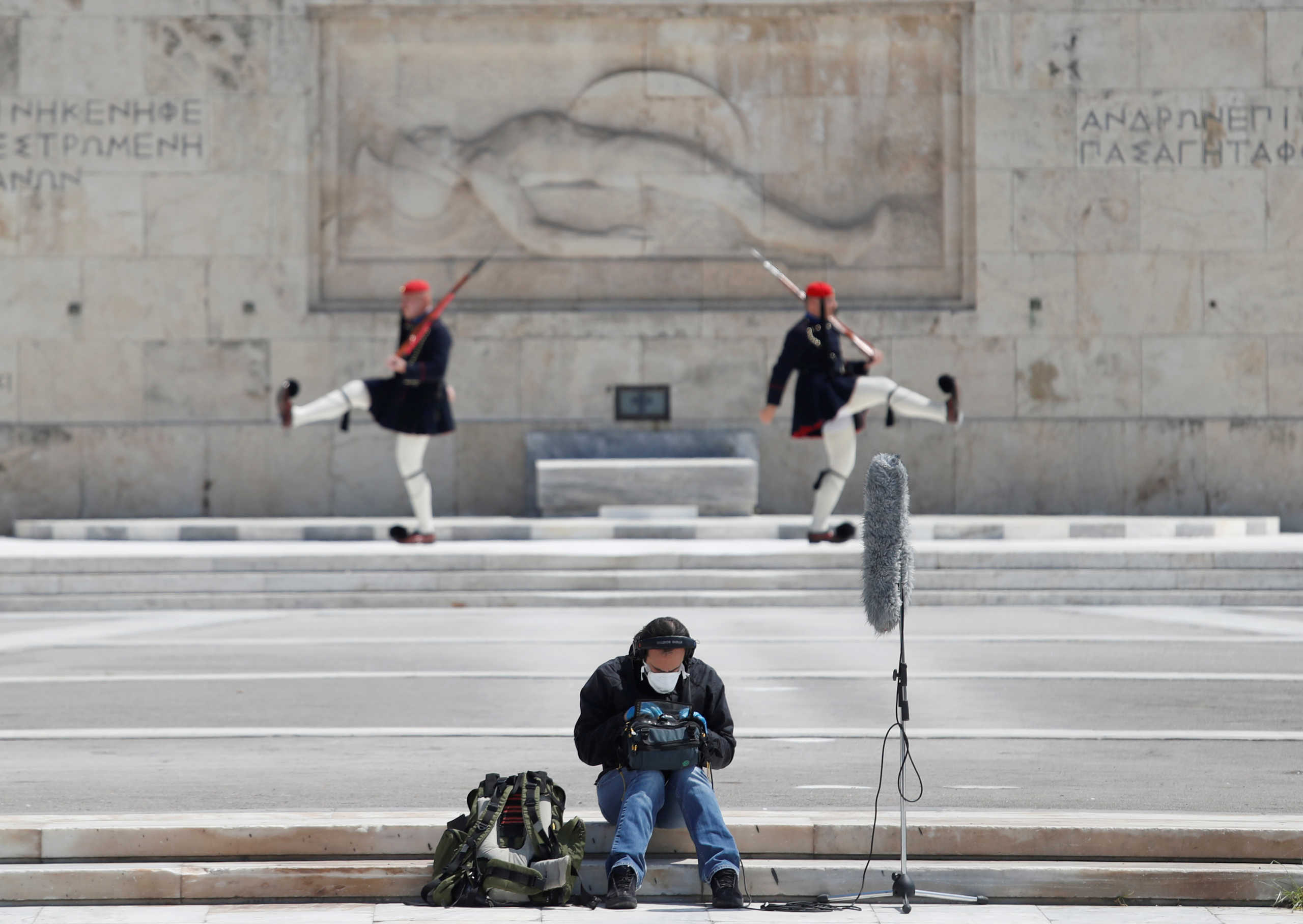 A journalist sits outside the Greek parliament following the coronavirus disease (COVID-19) outbreak in Athens, Greece, April 14, 2020. REUTERS