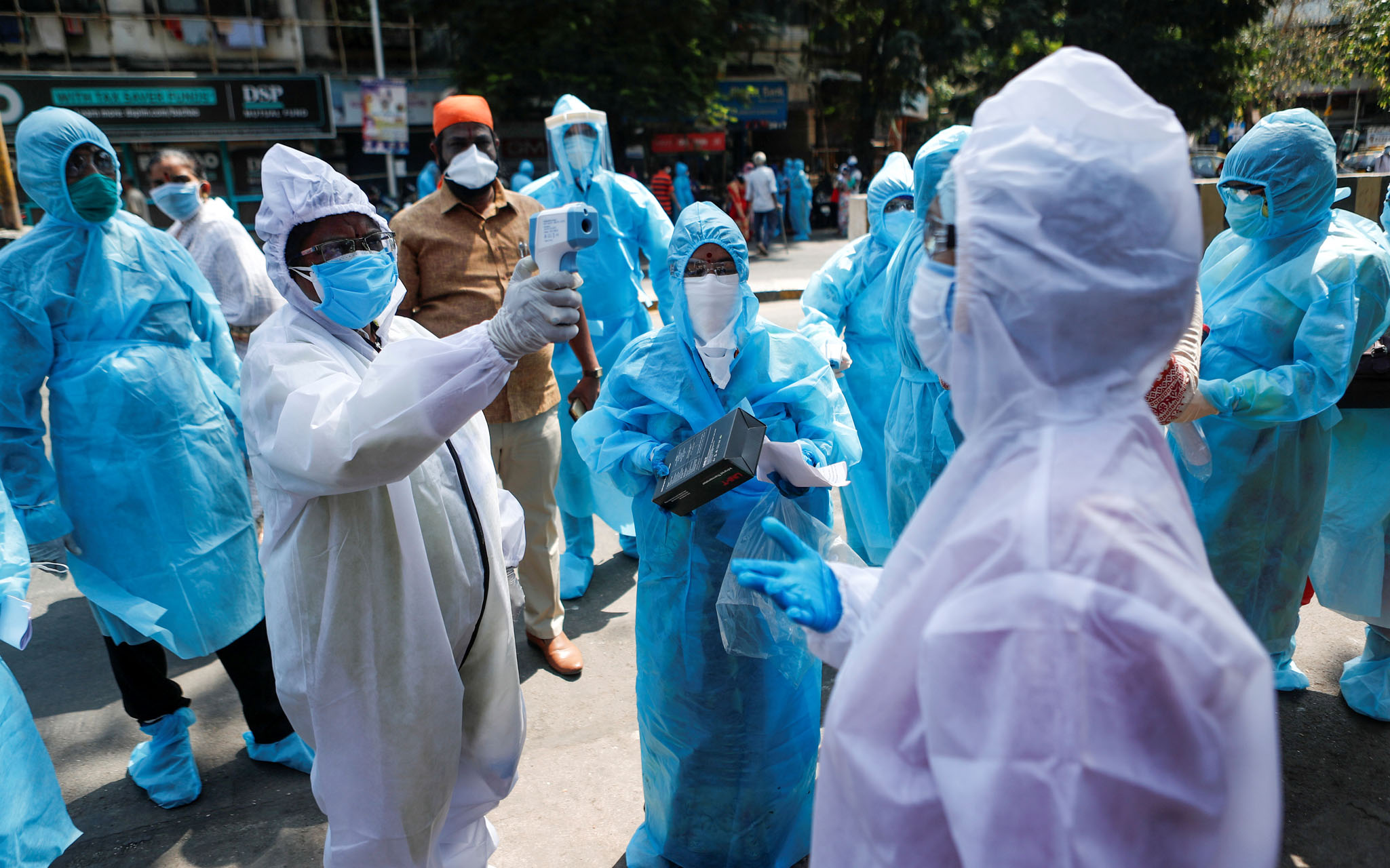 A healthcare worker checks the temperature of another worker using an infrared thermometer during a nationwide lockdown to slow the spreading of the coronavirus disease (COVID-19), in Mumbai, India, April 20, 2020. REUTERS