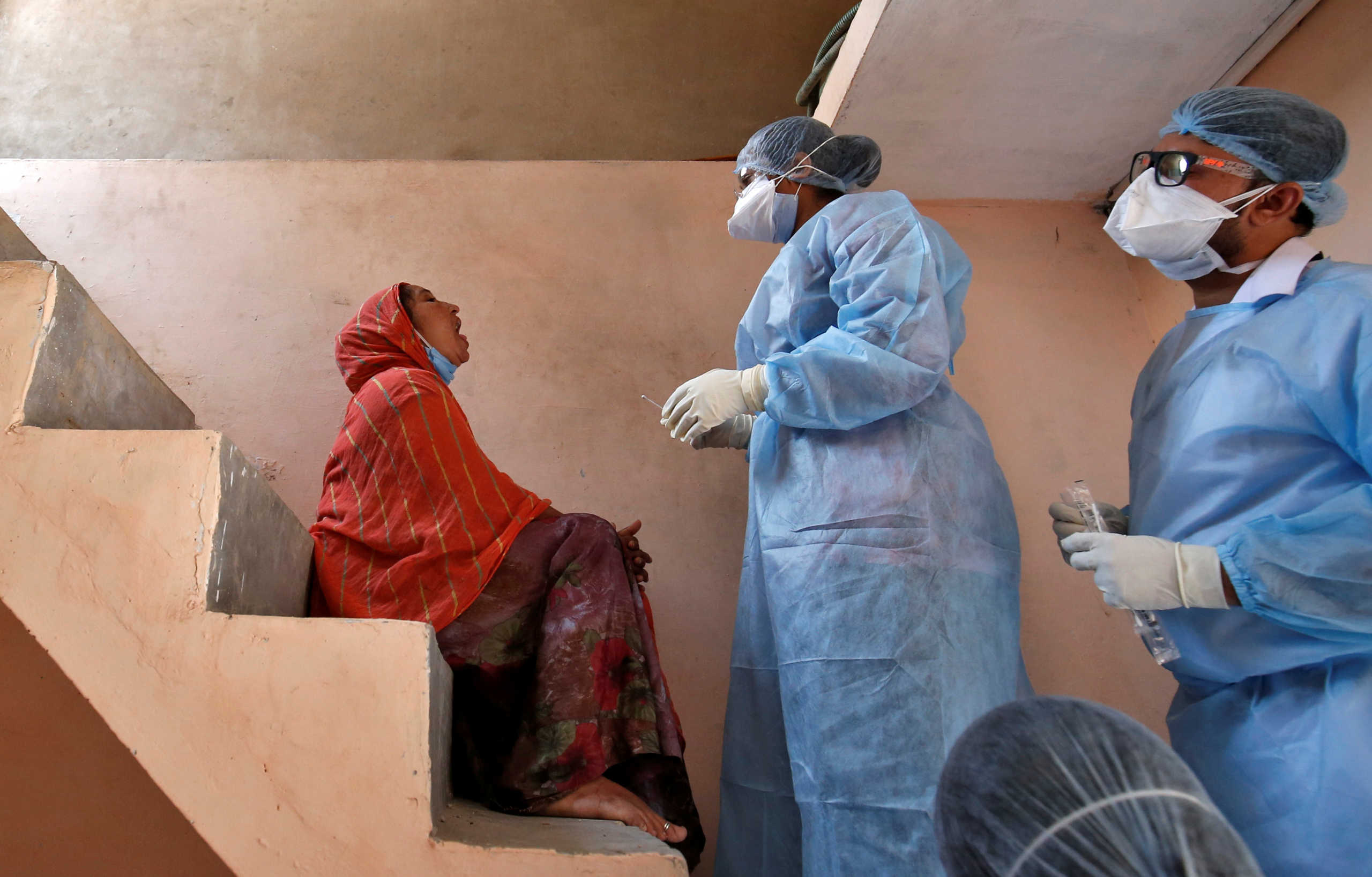 Doctors wearing protective gear prepare to take a swab from a woman to test for coronavirus disease (COVID-19) at a residential area in Ahmedabad, India, April 9, 2020. REUTERS