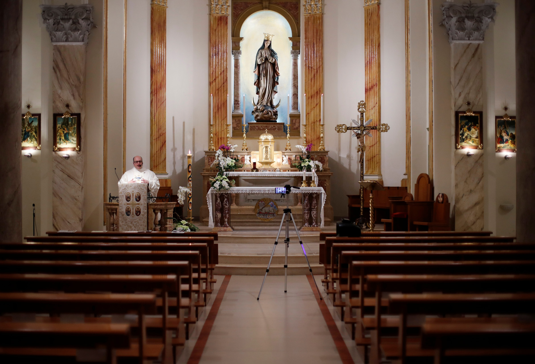 Priest Don Giancarlo Ruggieri livestreams an Easter Sunday mass with pictures of members of the congregation attached to the church's benches, as Italy celebrates Easter under lockdown, due to the outbreak of the coronavirus disease (COVID-19), in the small southern town of San Giorgio Ionico, Itay April 12, 2020. REUTERS