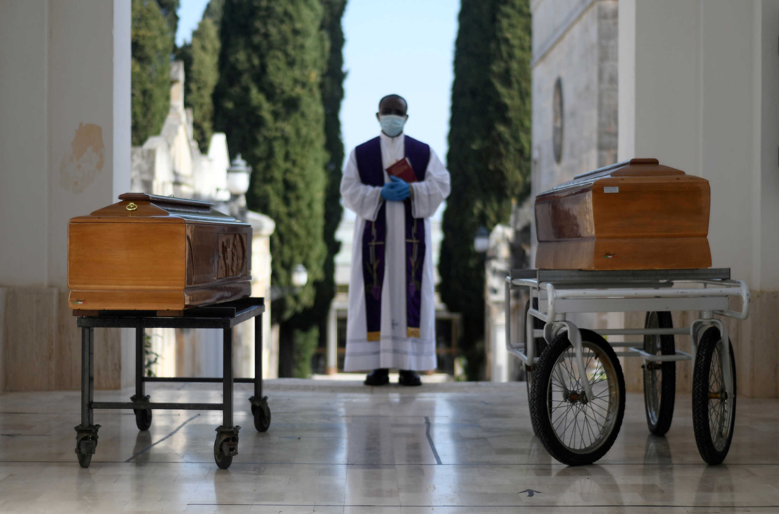 FILE PHOTO: Coffins of two victims of coronavirus disease (COVID-19) are seen during a burial ceremony in the southern town of Cisternino, Italy March 30, 2020. REUTERS