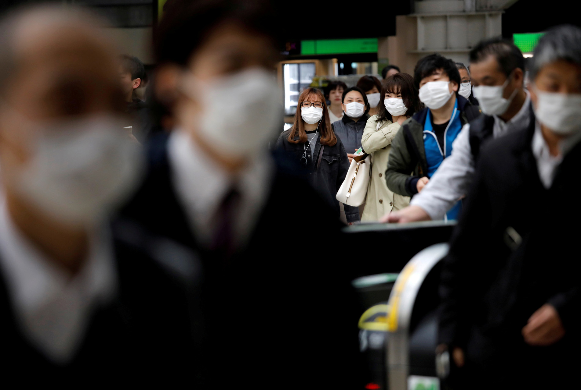 FILE PHOTO: Passengers wearing protective face masks, following an outbreak of the coronavirus disease (COVID-19), are seen at a station after the government announced the state of emergency for the capital following the disease outbreak in Tokyo, Japan April 8, 2020.  REUTERS