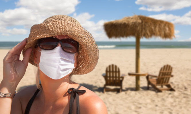 Vacationing Woman Wearing Face Mask on Sandy Beach..