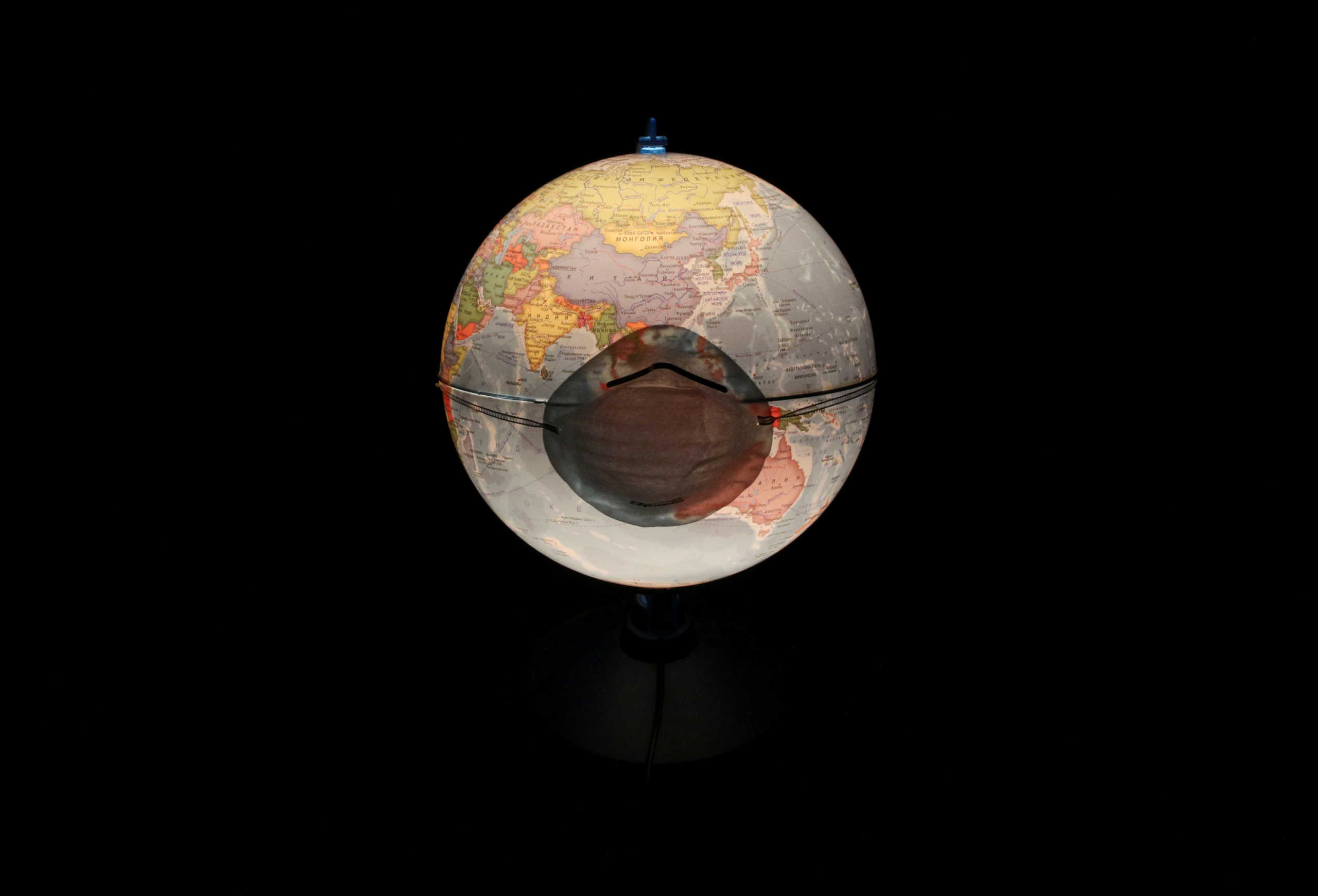 FILE PHOTO: A protective mask, which is widely used as a preventive measure against the coronavirus (COVID-19), is pictured on a table world globe in this illustration taken March 17, 2020. REUTERS