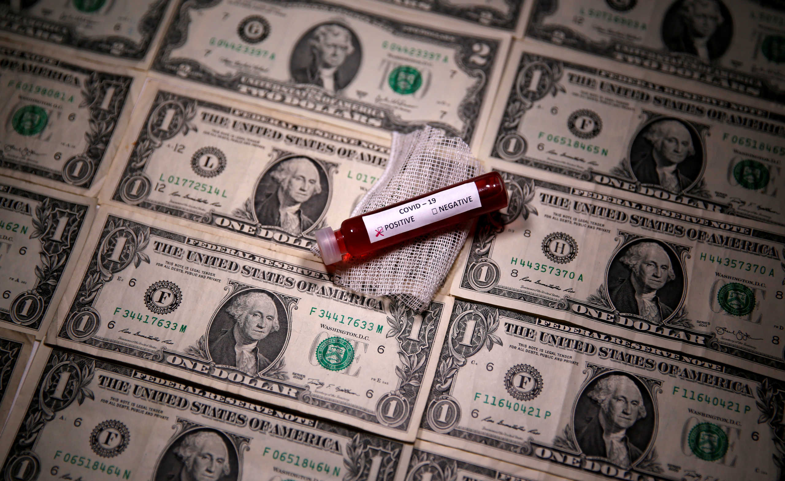 FILE PHOTO: Test tube with fake blood labelled with the coronavirus disease (COVID-19) is placed on dollar banknotes in this illustration taken March 27, 2020. REUTERS