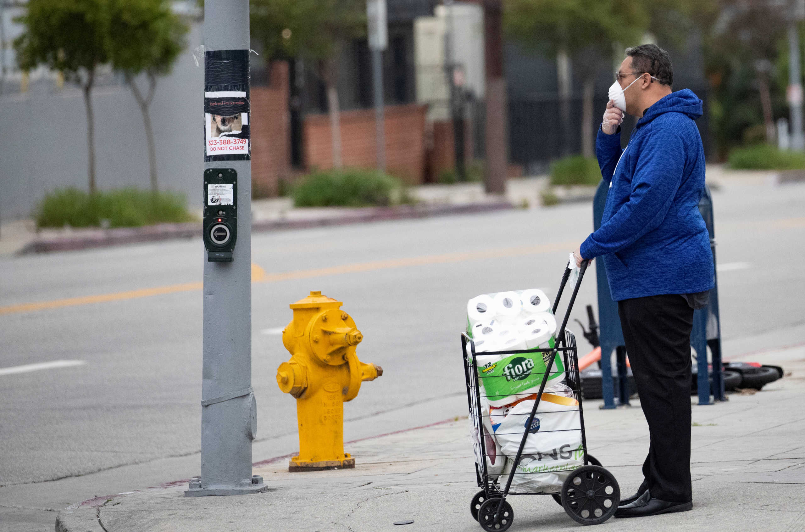 A person wearing a face mask waits to cross a street during the global outbreak of the coronavirus disease (COVID-19), in Los Angeles, California, U.S., April 18, 2020. REUTERS