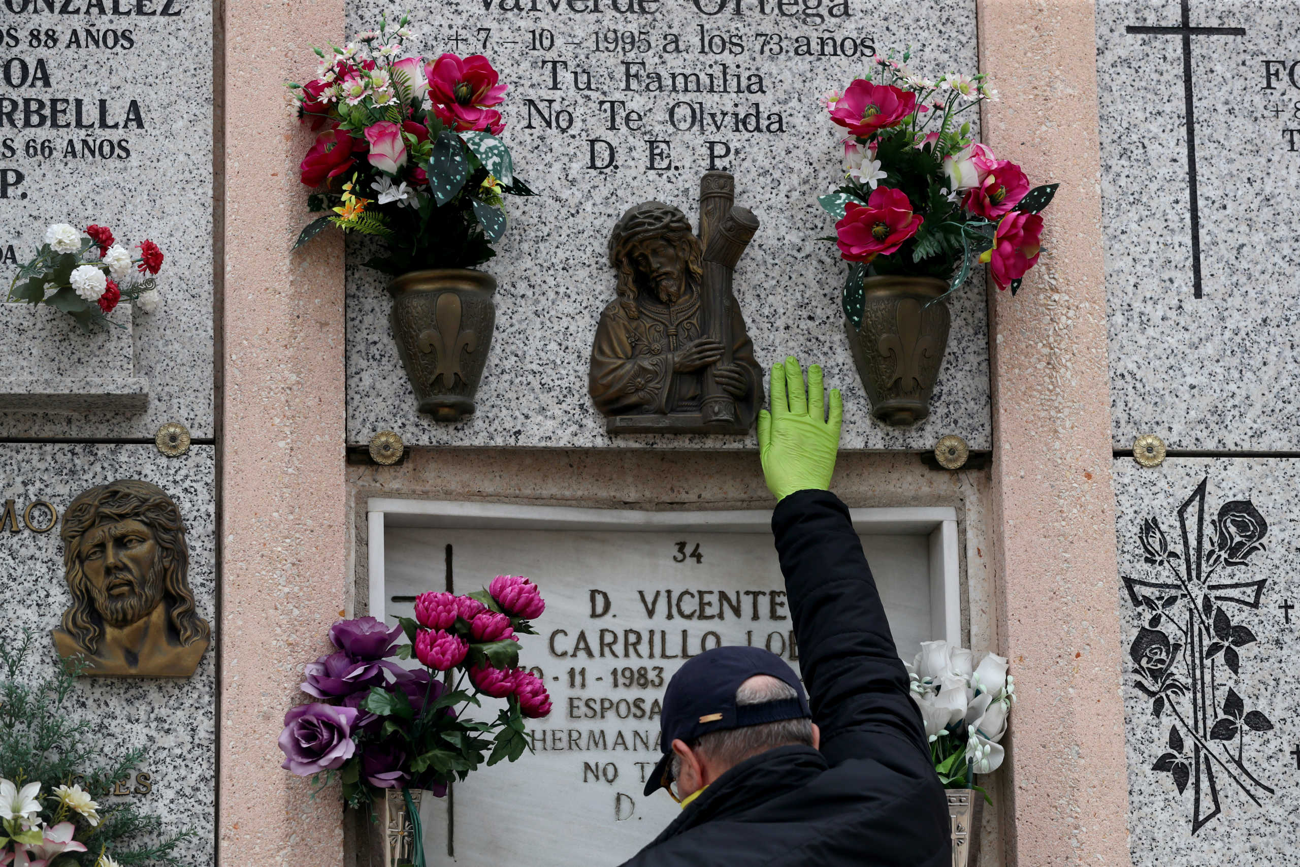 Carolina Navarro's son touches the headstone of his parents' niche with a protective glove after the burial of his mother, during the coronavirus disease (COVID-19) outbreak, at a cemetery in Madrid, Spain, April 7, 2020. Although Navarro did not die of coronavirus disease (COVID-19) her family could not be with her after her death due to the lockdown, and had to wait a whole week to celebrate her burial. REUTERS