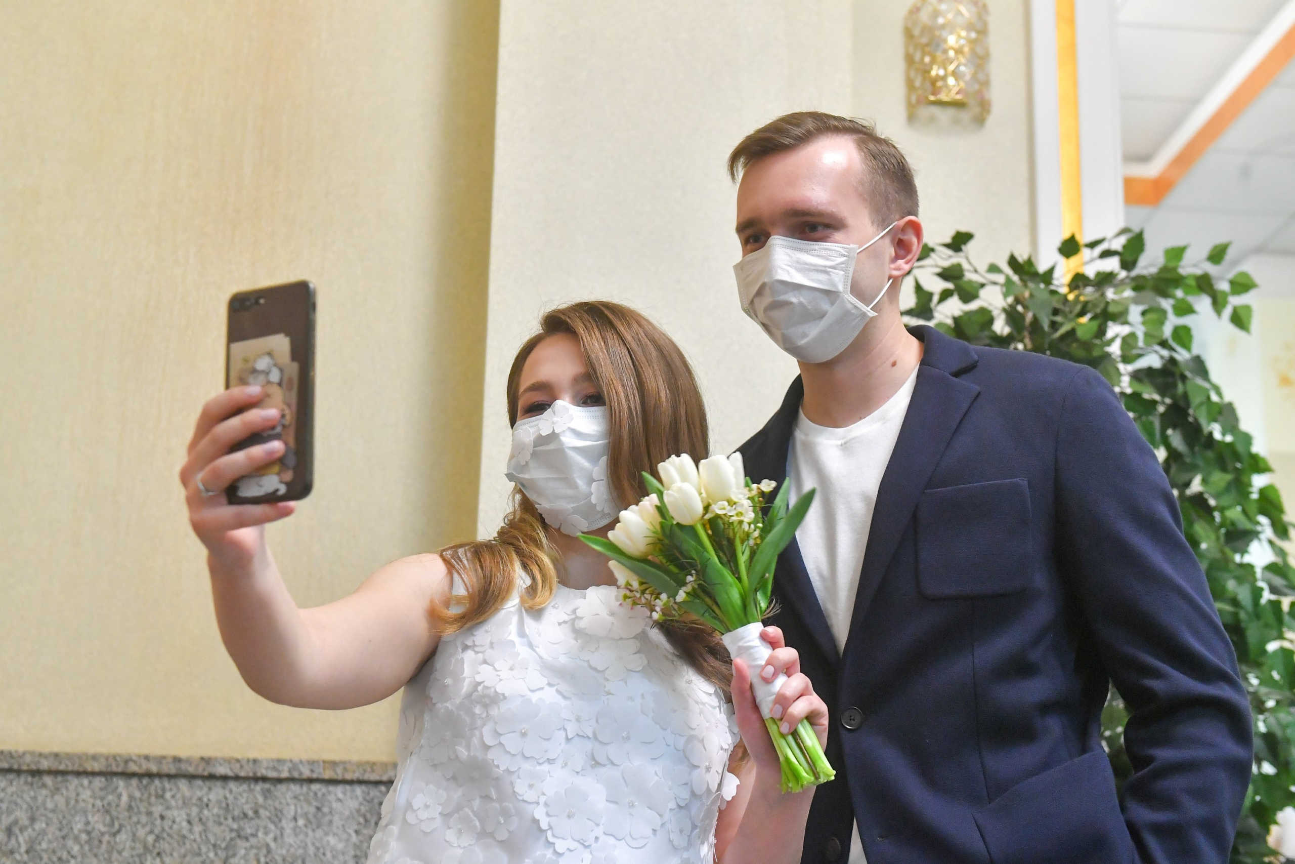 An engaged couple wearing protective masks pose for a selfie at a marriage registration palace, which is empty amid the coronavirus pandemic in Moscow, Russia April 8, 2020. Moscow authorities imposed restrictions on public gatherings and announced a partial lockdown ordering residents to stay at home to prevent the spread of coronavirus disease (COVID-19). Sergei Kiselyov