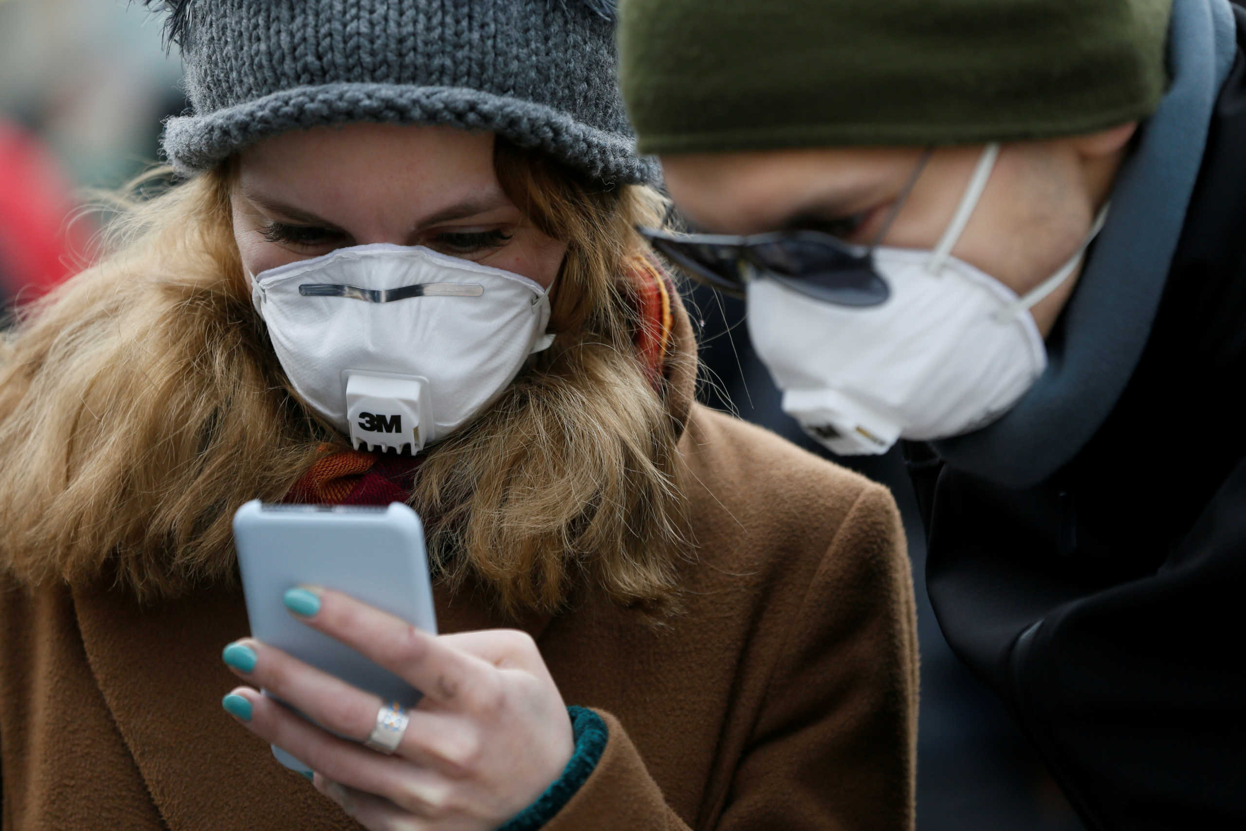 FILE PHOTO: People wearing protective face masks use a smartphone on a street amid coronavirus (COVID-19) concerns in Kiev, Ukraine March 17, 2020.  REUTERS