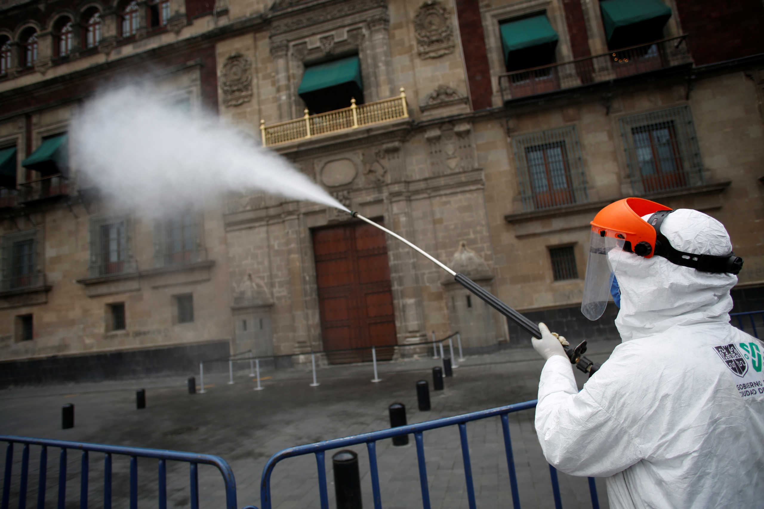 Workers spray disinfectant in front of the National Palace in Zocalo Square after Mexico entered what the government calls "Phase 3" of the spread of the coronavirus disease (COVID-19), in Mexico City, Mexico April 21, 2020. REUTERS